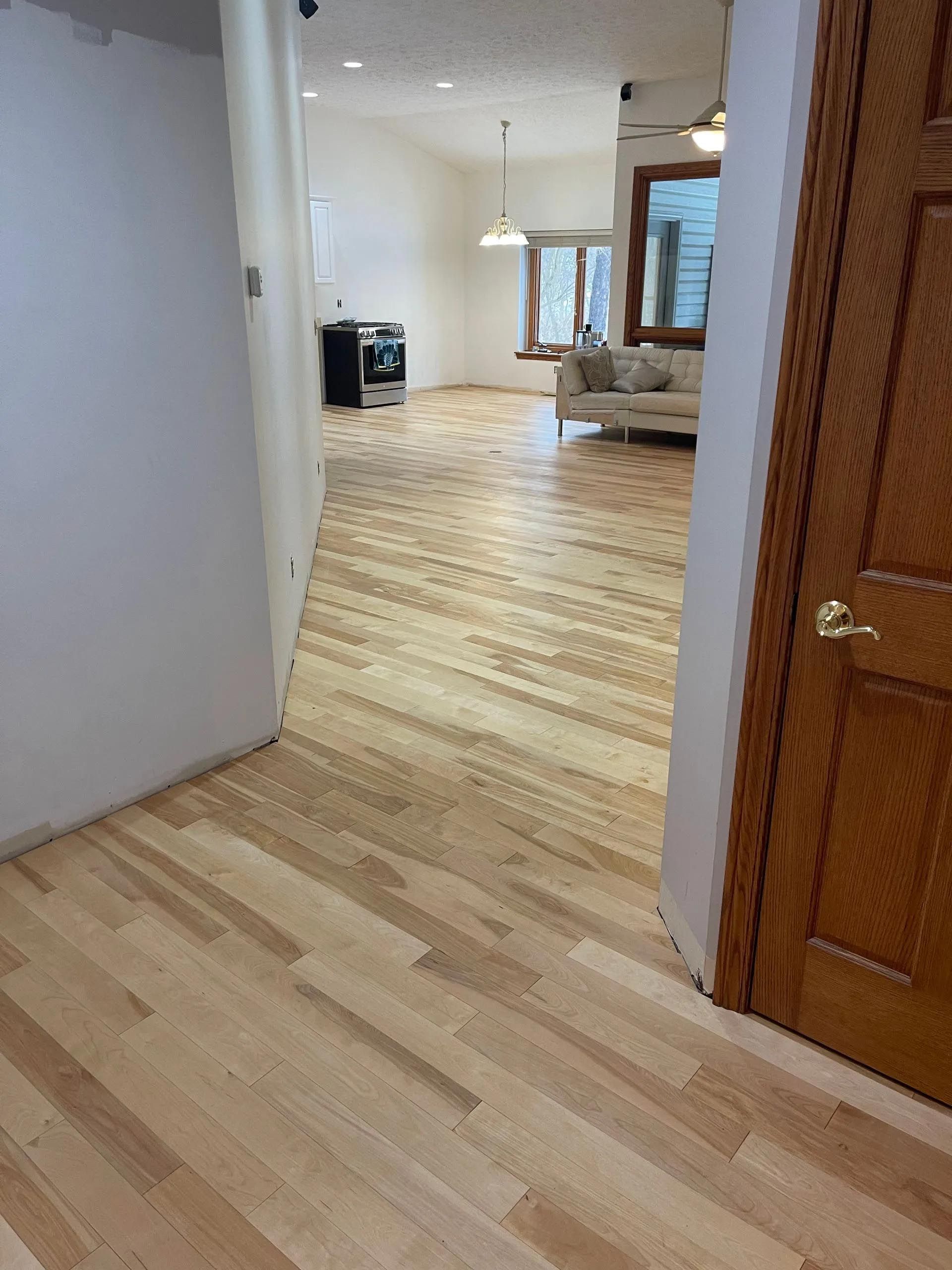 A hallway with hardwood floors leading to a living room.