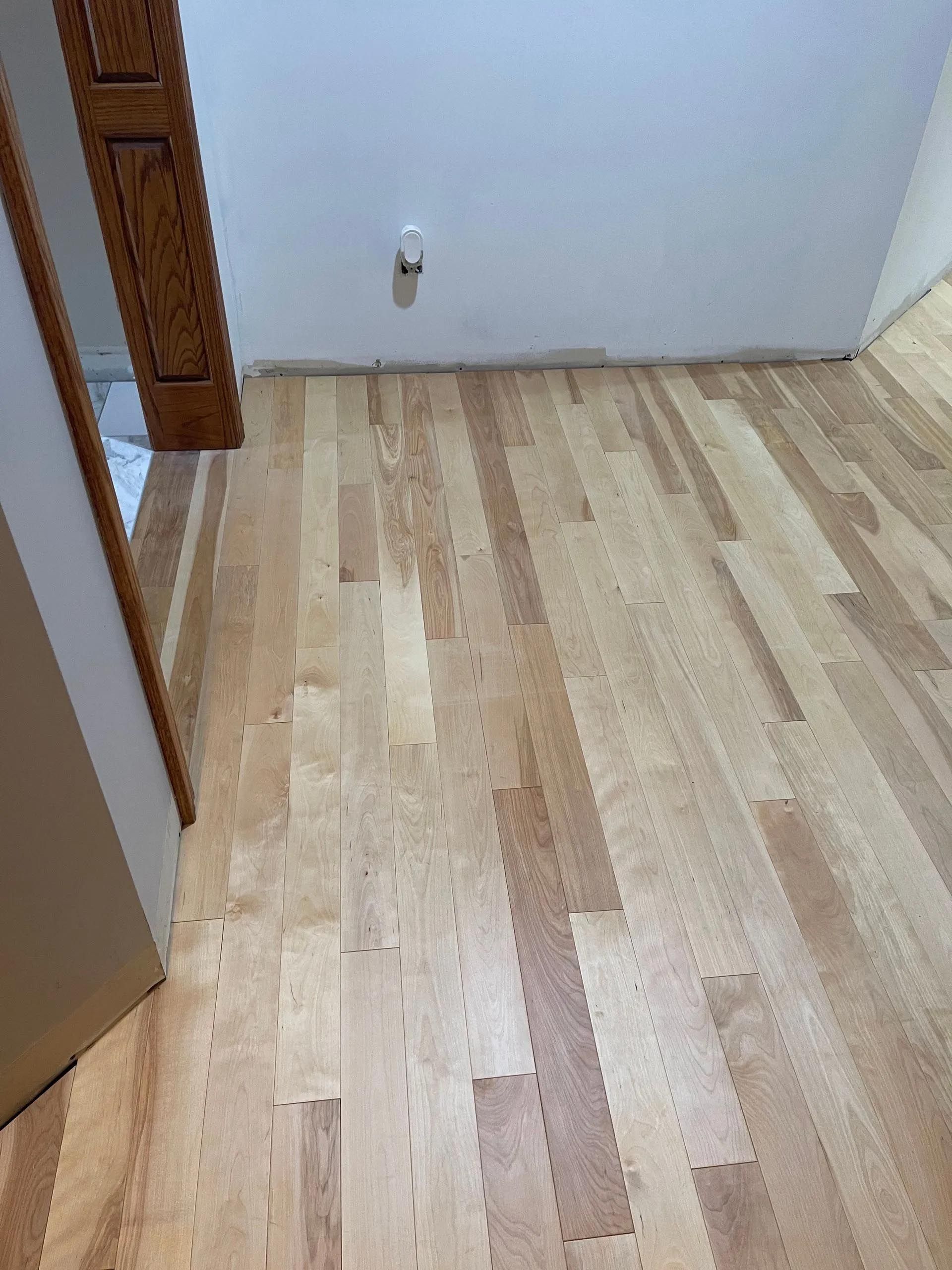 A room with a wooden floor and a white wall.