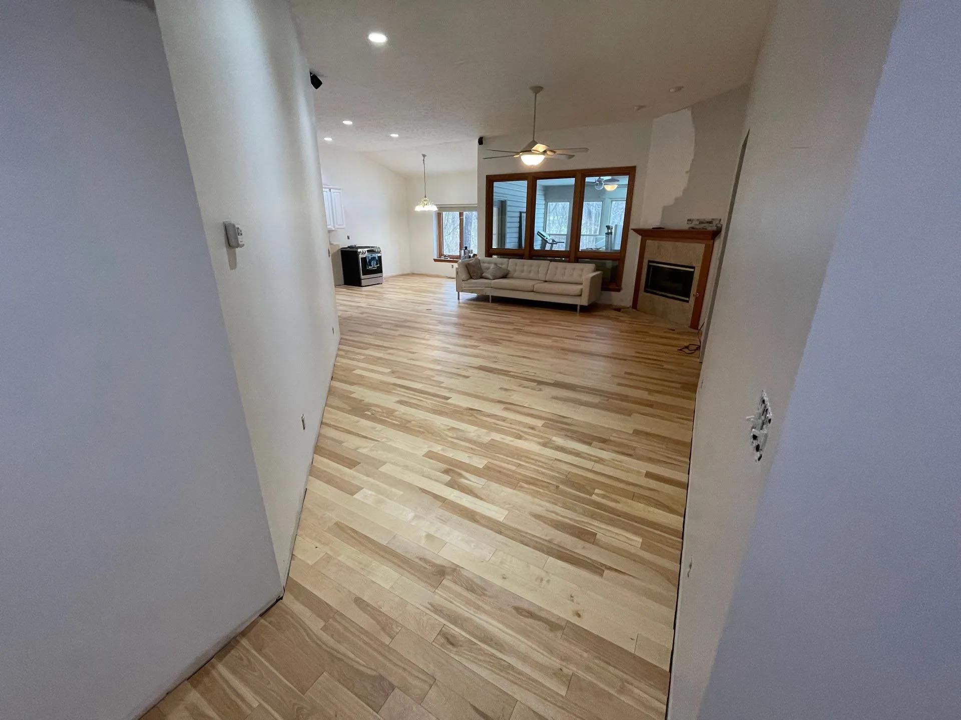 A hallway leading to a living room with hardwood floors and a couch.