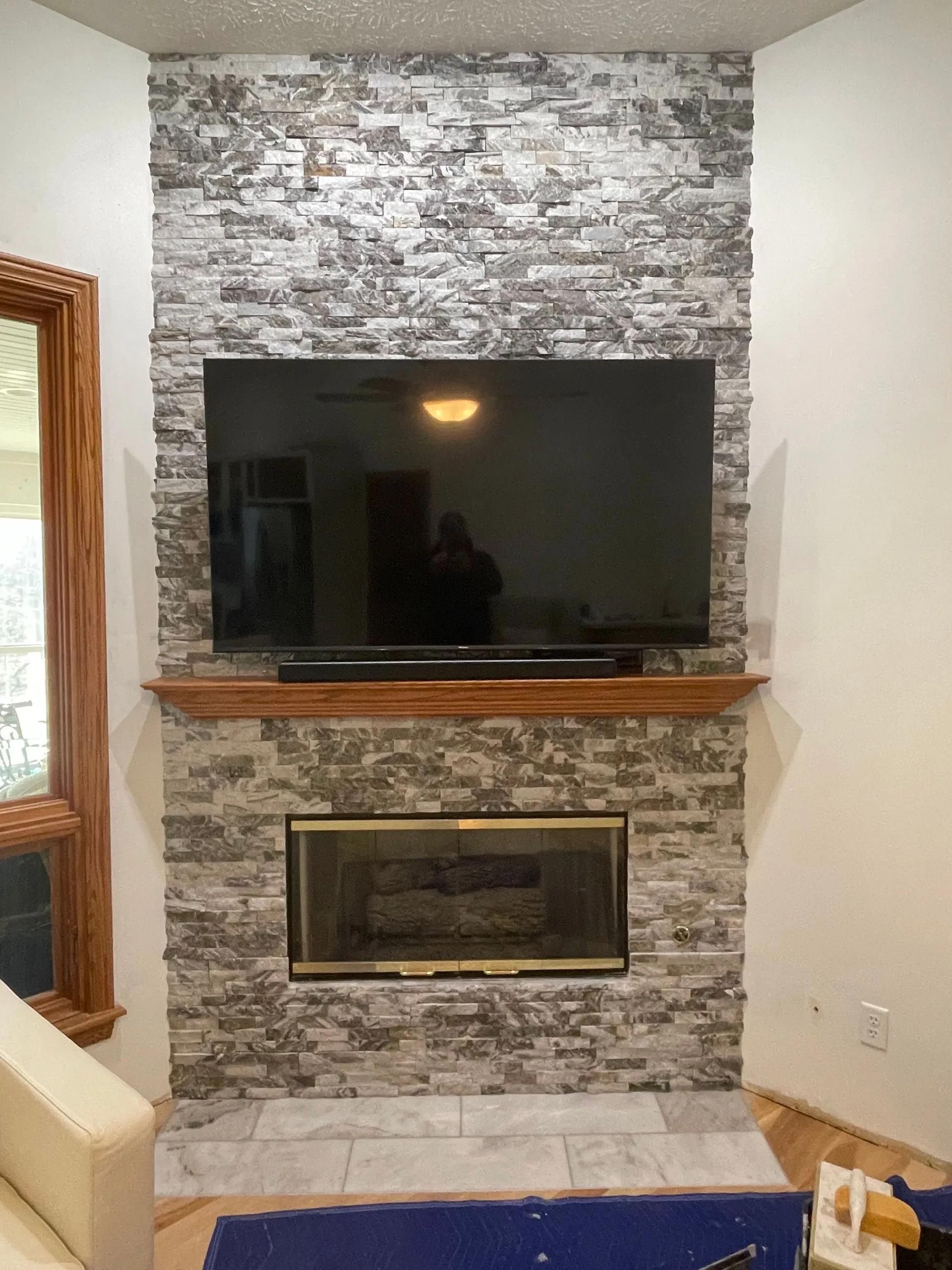 A living room with a fireplace and a flat screen tv on the wall.
