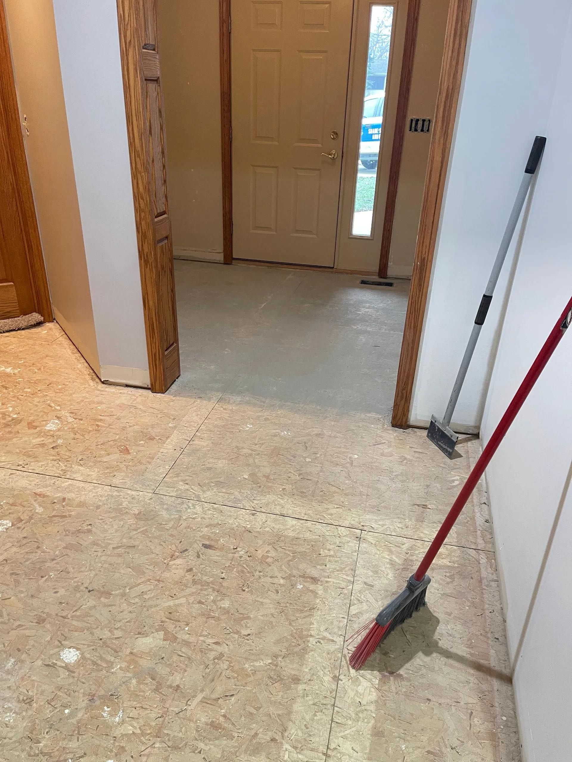A broom is sitting on the floor in a hallway next to a door.