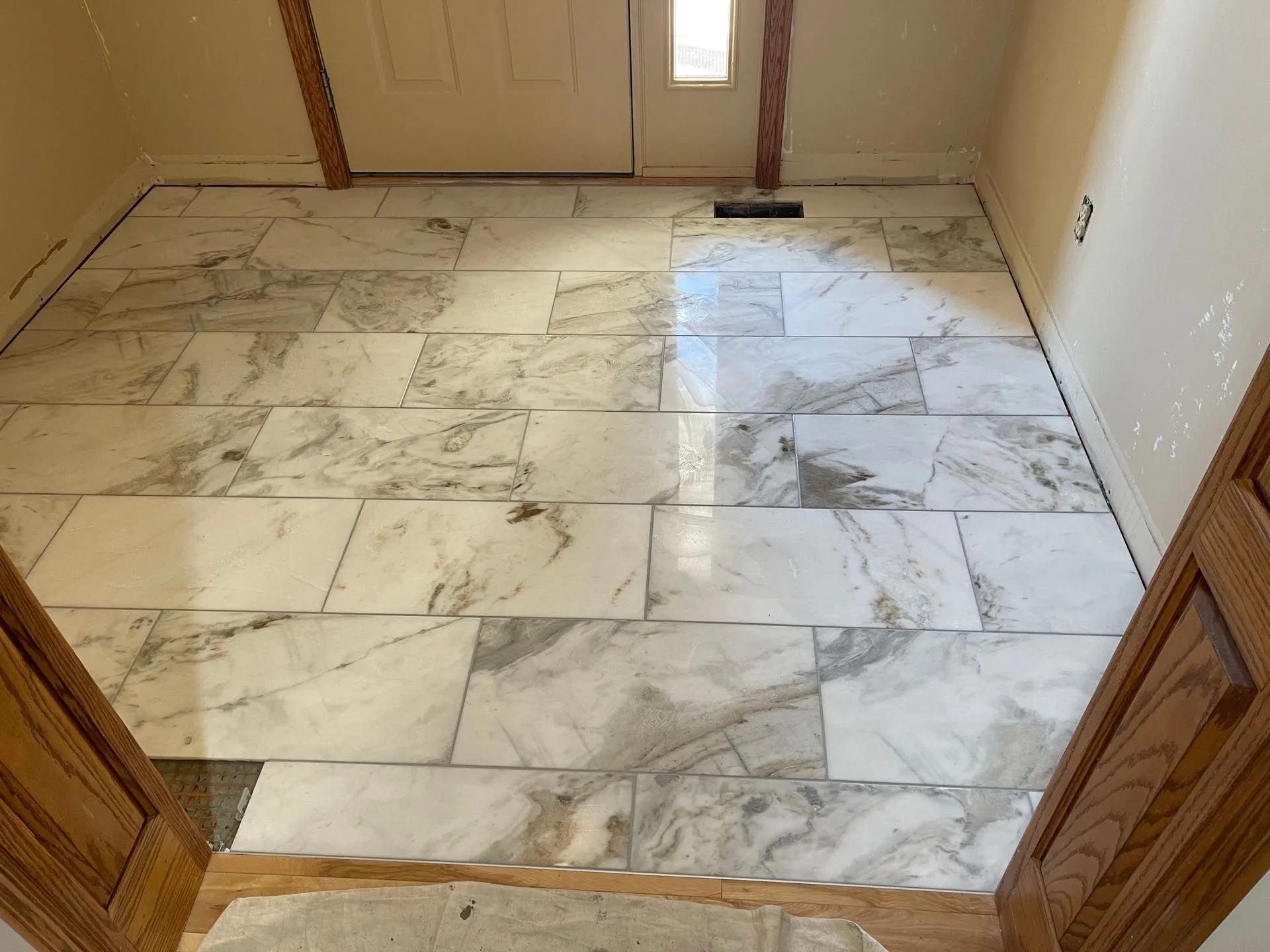 A hallway with marble tiles on the floor and a door.
