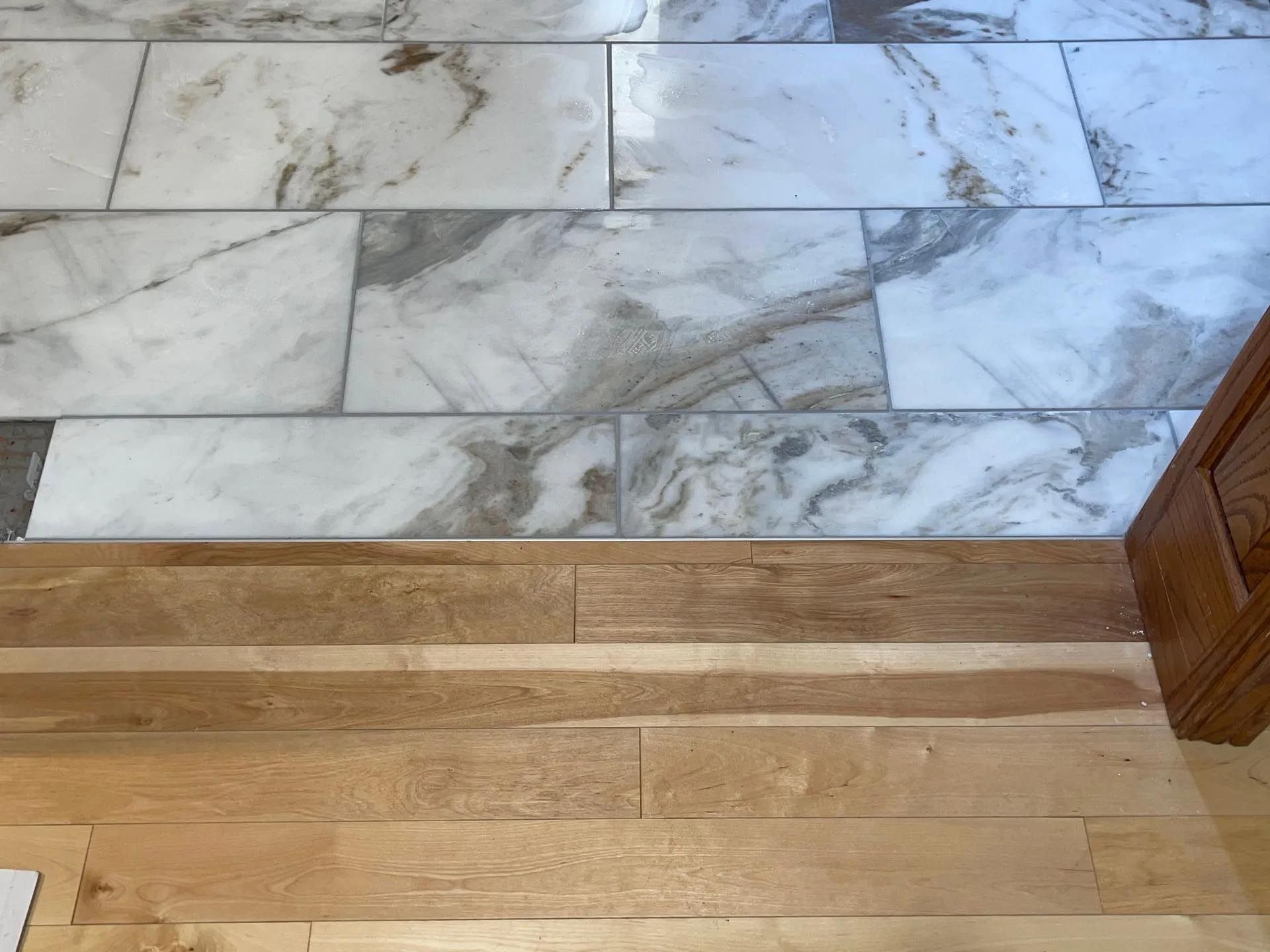 A wooden floor next to a marble tile floor