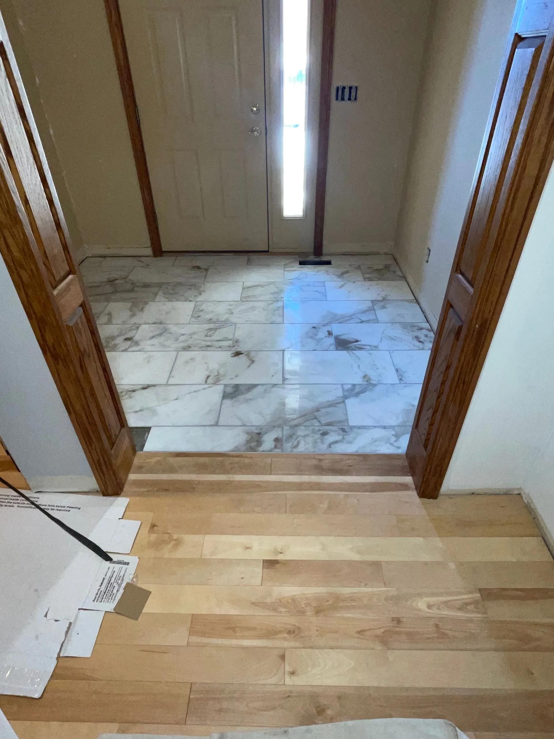 A hallway with wooden floors and marble tiles.
