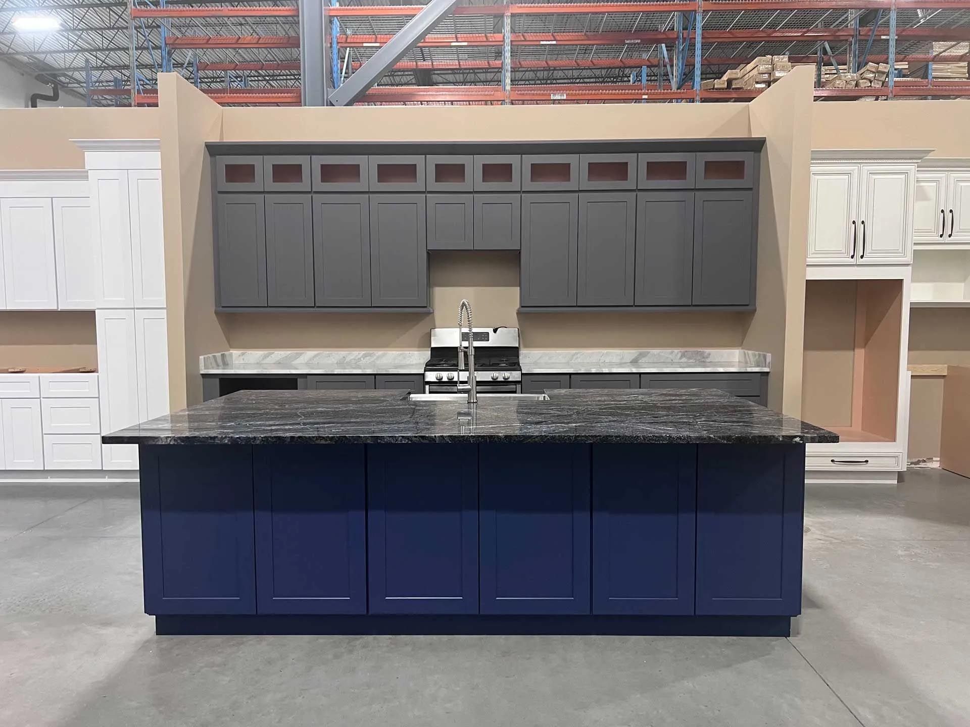 A kitchen with gray cabinets and a blue island in a warehouse.