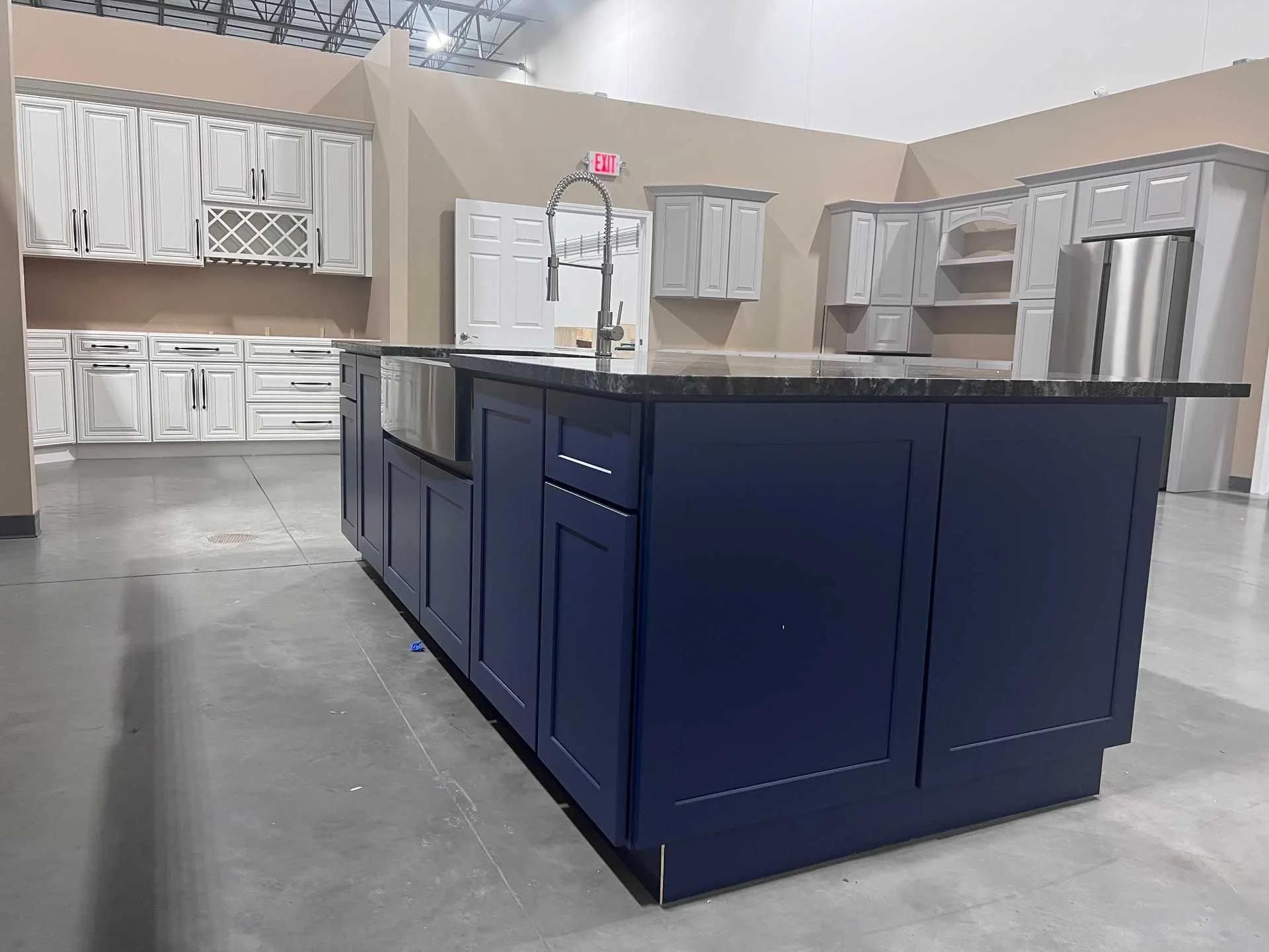 A kitchen with blue cabinets and a large island in the middle.