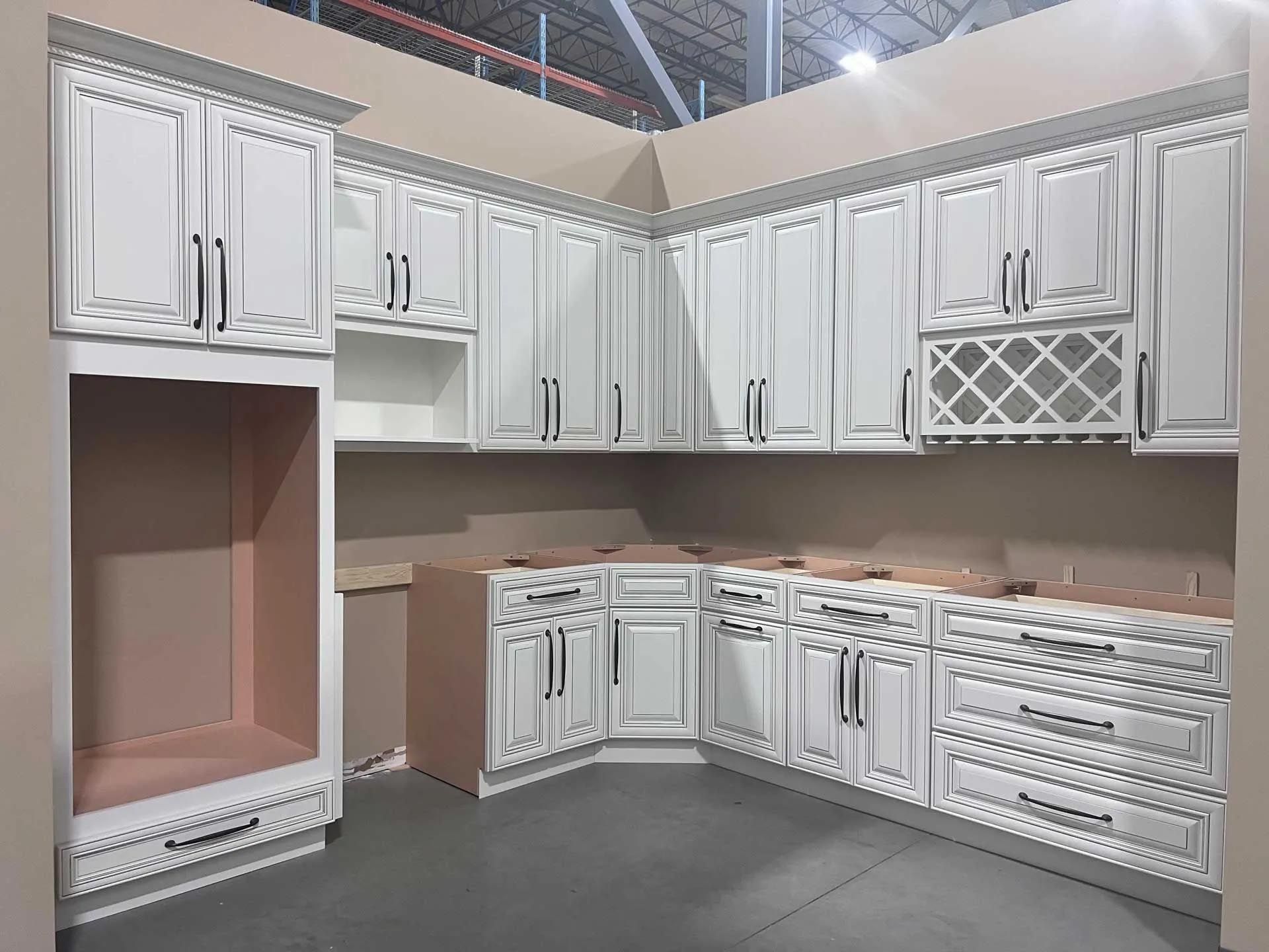 A kitchen with white cabinets and drawers is being built in a warehouse.