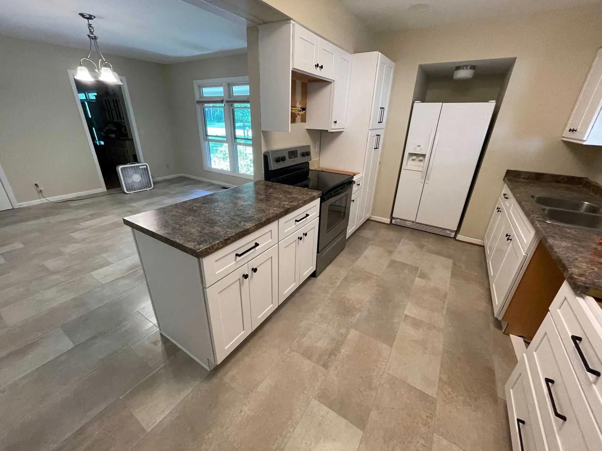 A kitchen with white cabinets , granite counter tops , stainless steel appliances , and a refrigerator.