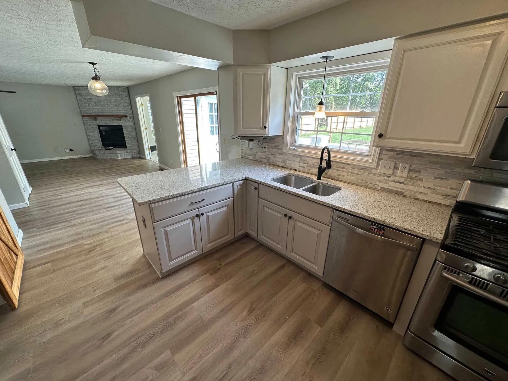 A kitchen with white cabinets , granite counter tops , stainless steel appliances and a sink.