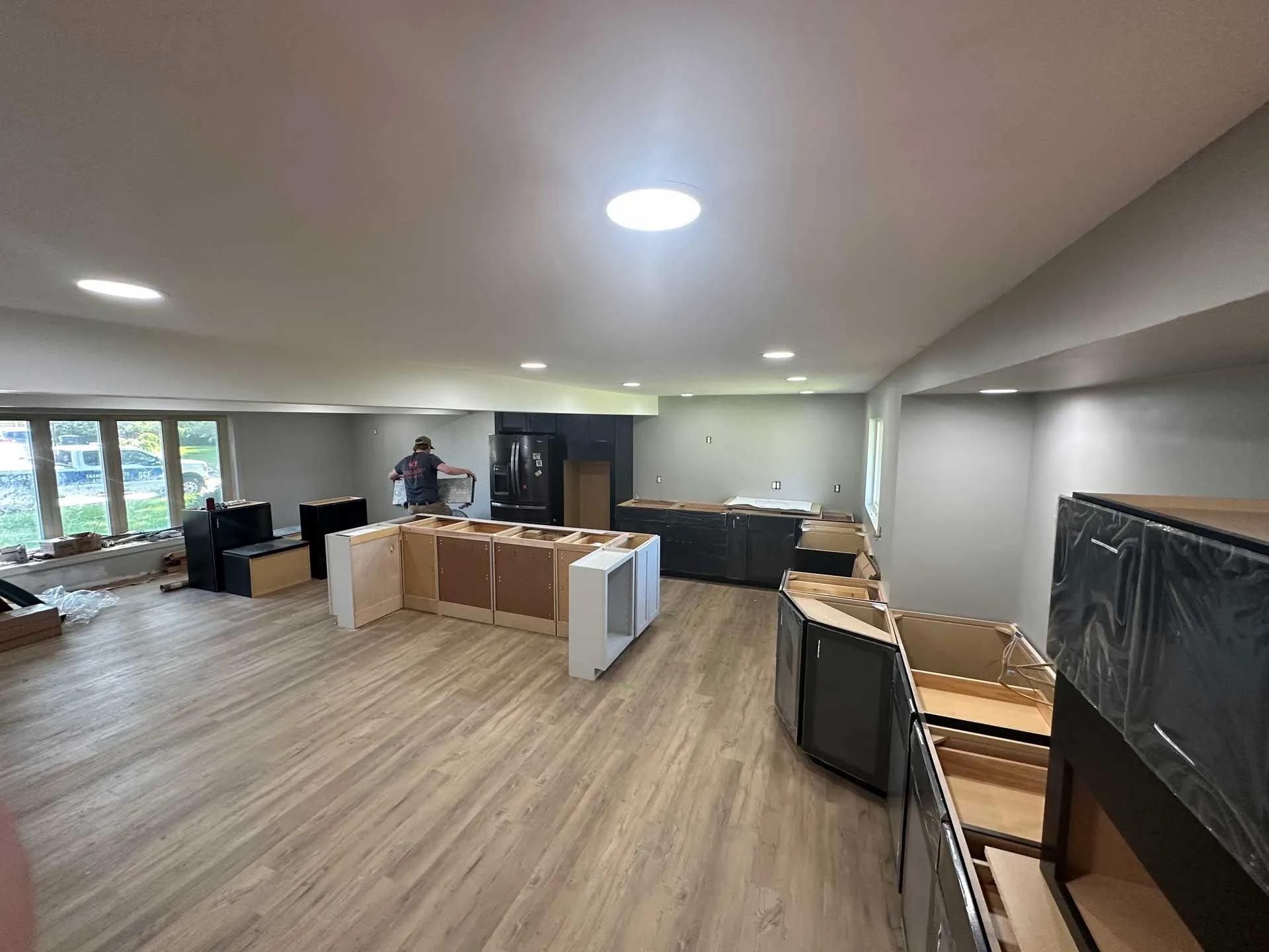 A large room with wooden floors and a man standing in the middle of it.