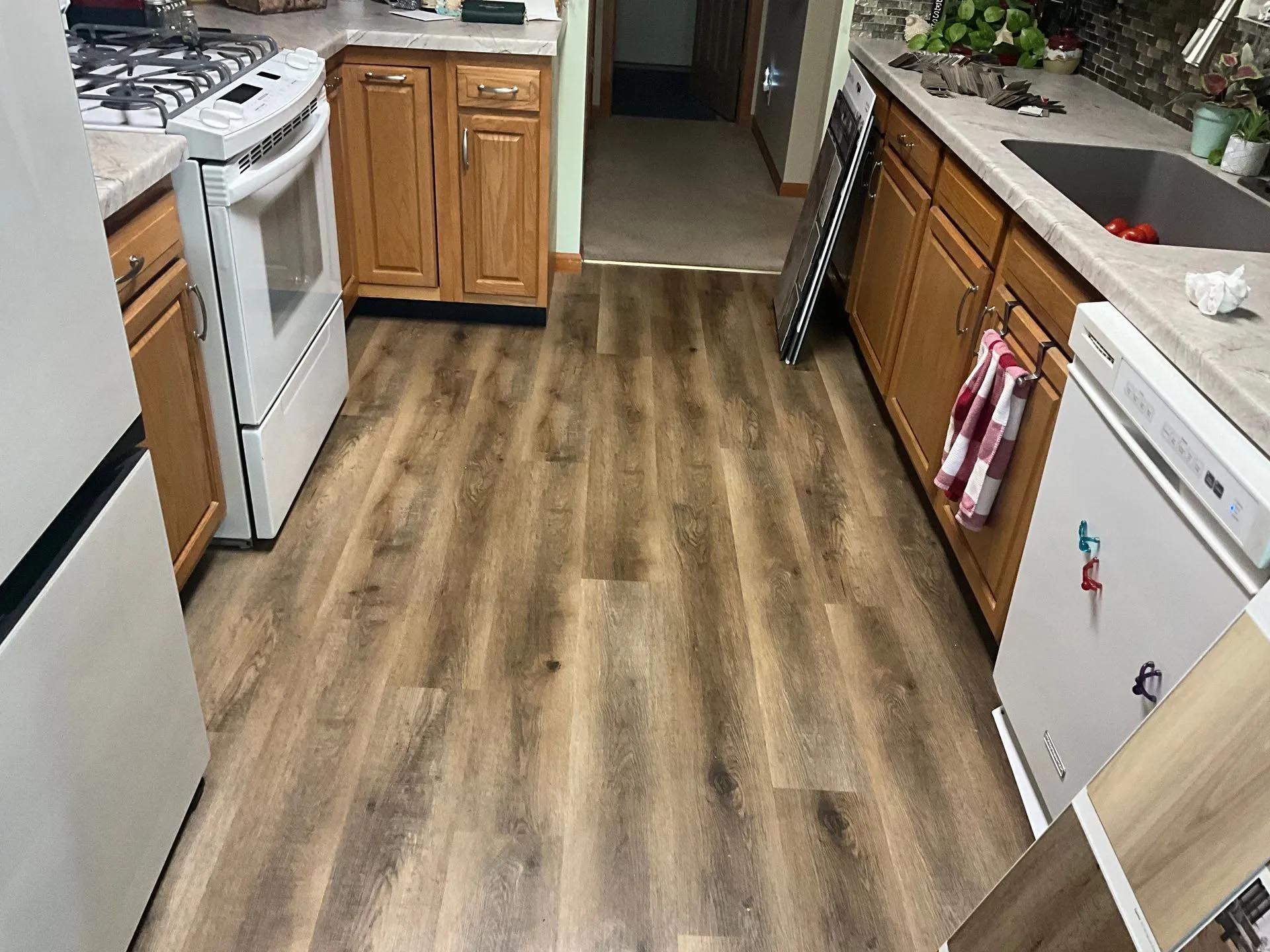 A kitchen with hardwood floors , a refrigerator , stove , sink and dishwasher.