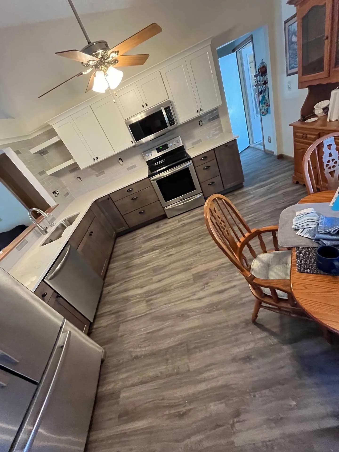 A kitchen with a table and chairs and a ceiling fan.