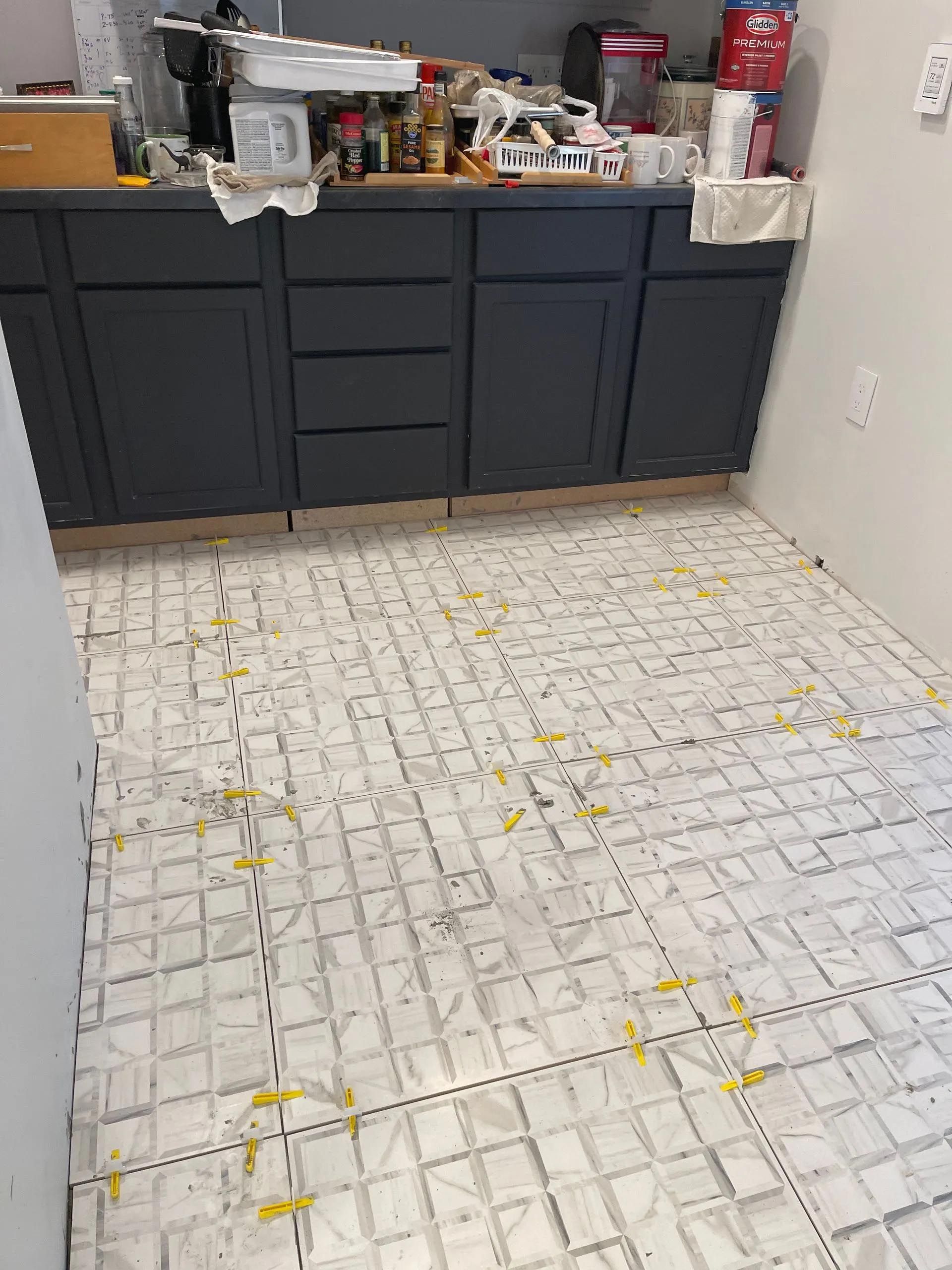 A kitchen with a brick floor and black cabinets.