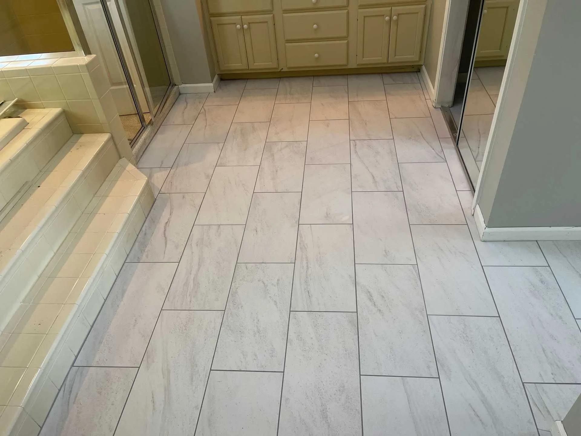 A bathroom with white tile floors and cabinets