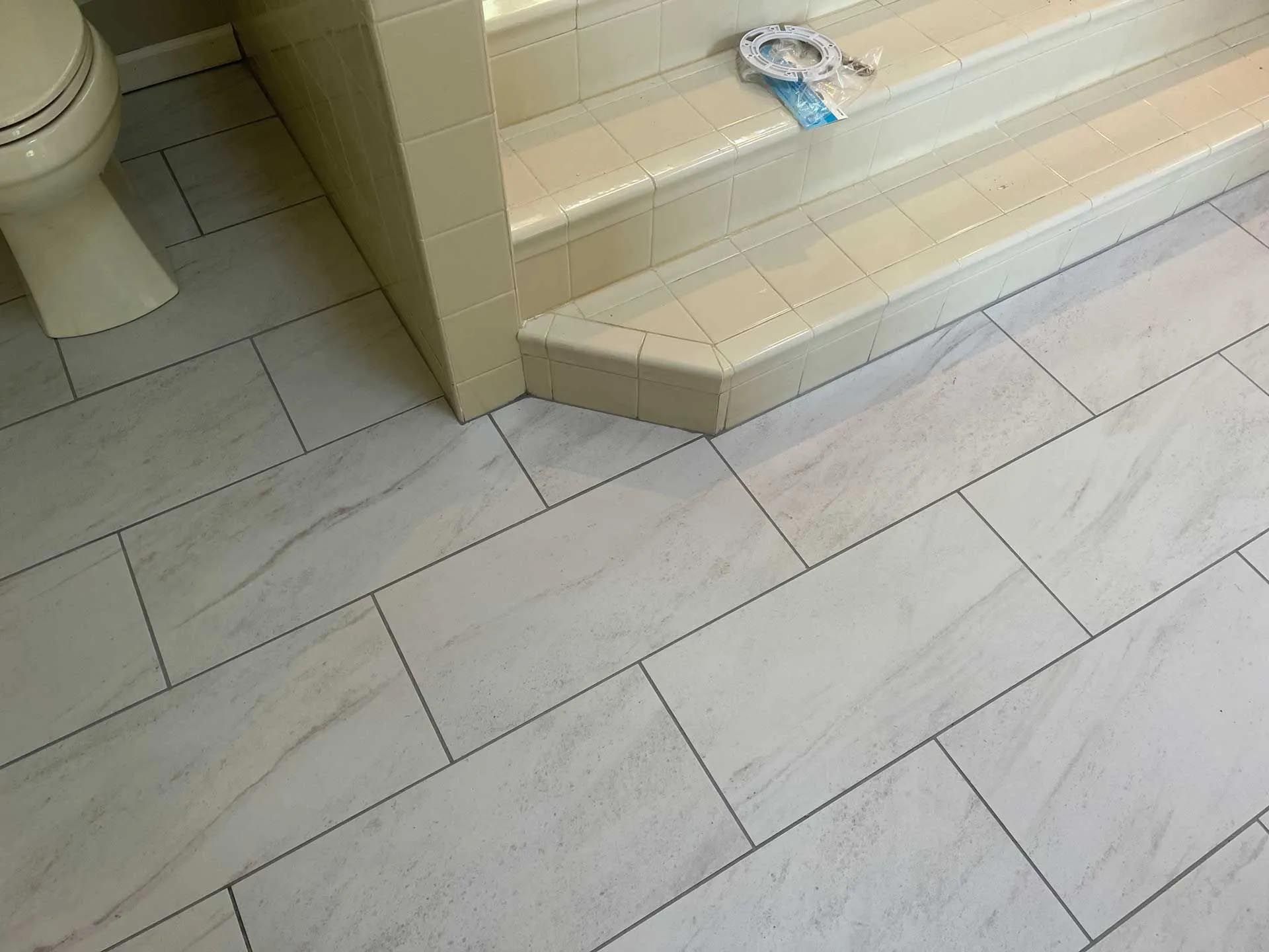 A bathroom with white tiles and a toilet and stairs