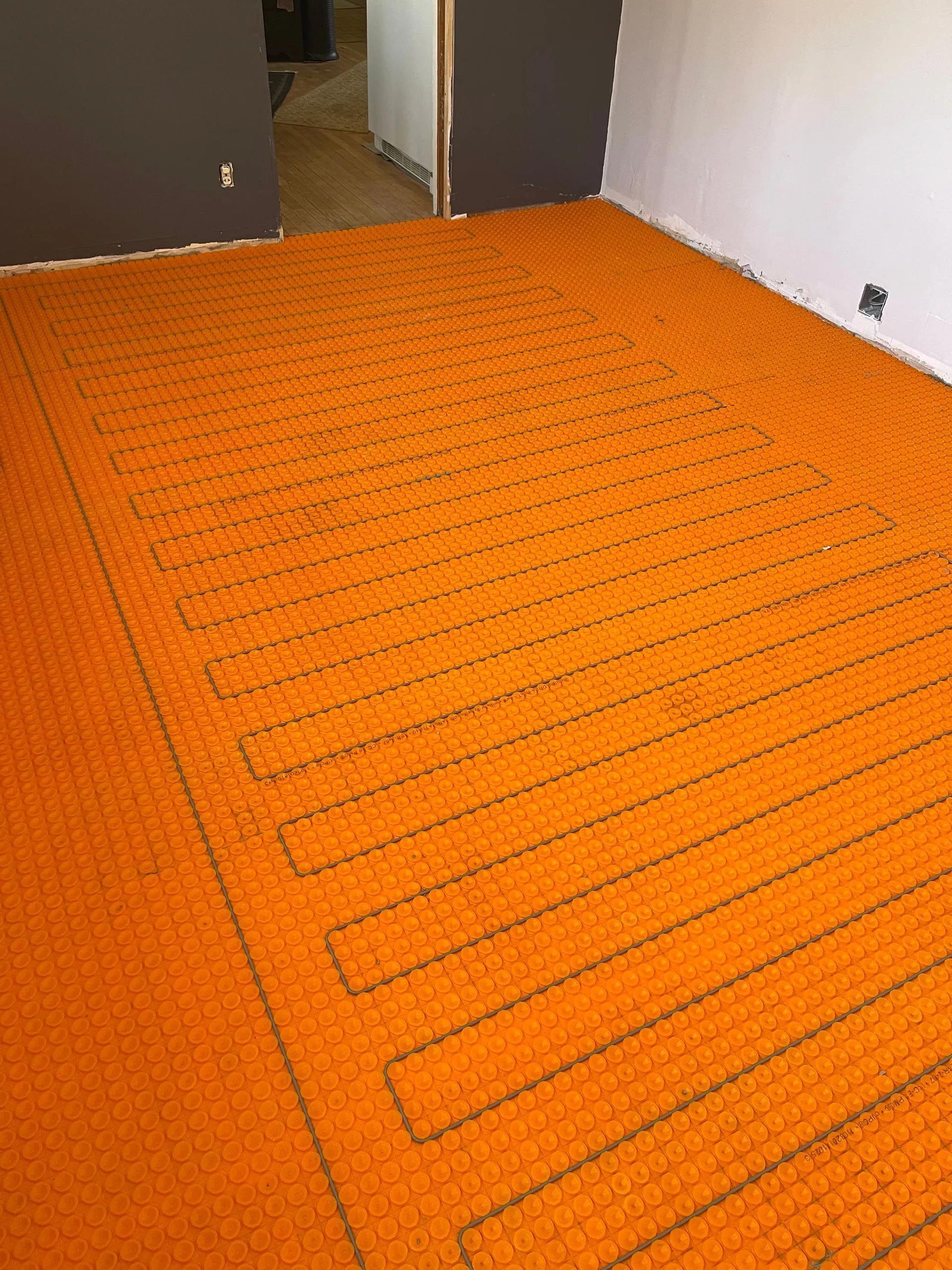 A room with a large orange rug on the floor.