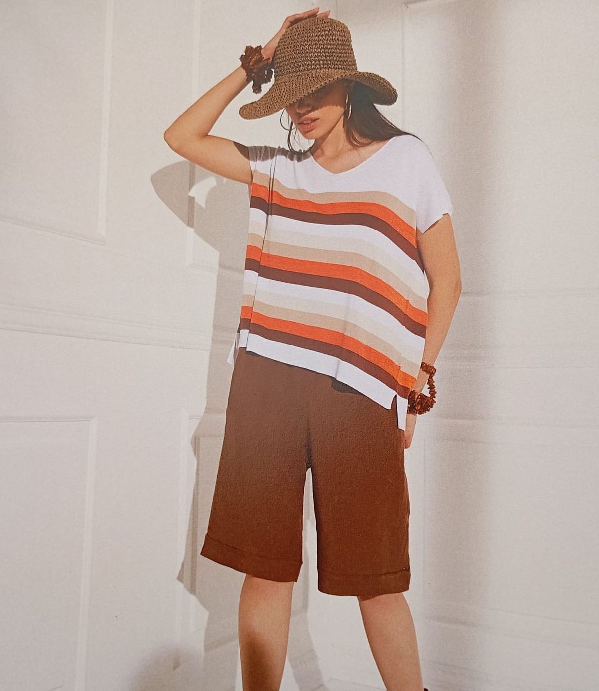 Una donna che indossa un cappello e pantaloncini corti è in piedi davanti a un muro bianco