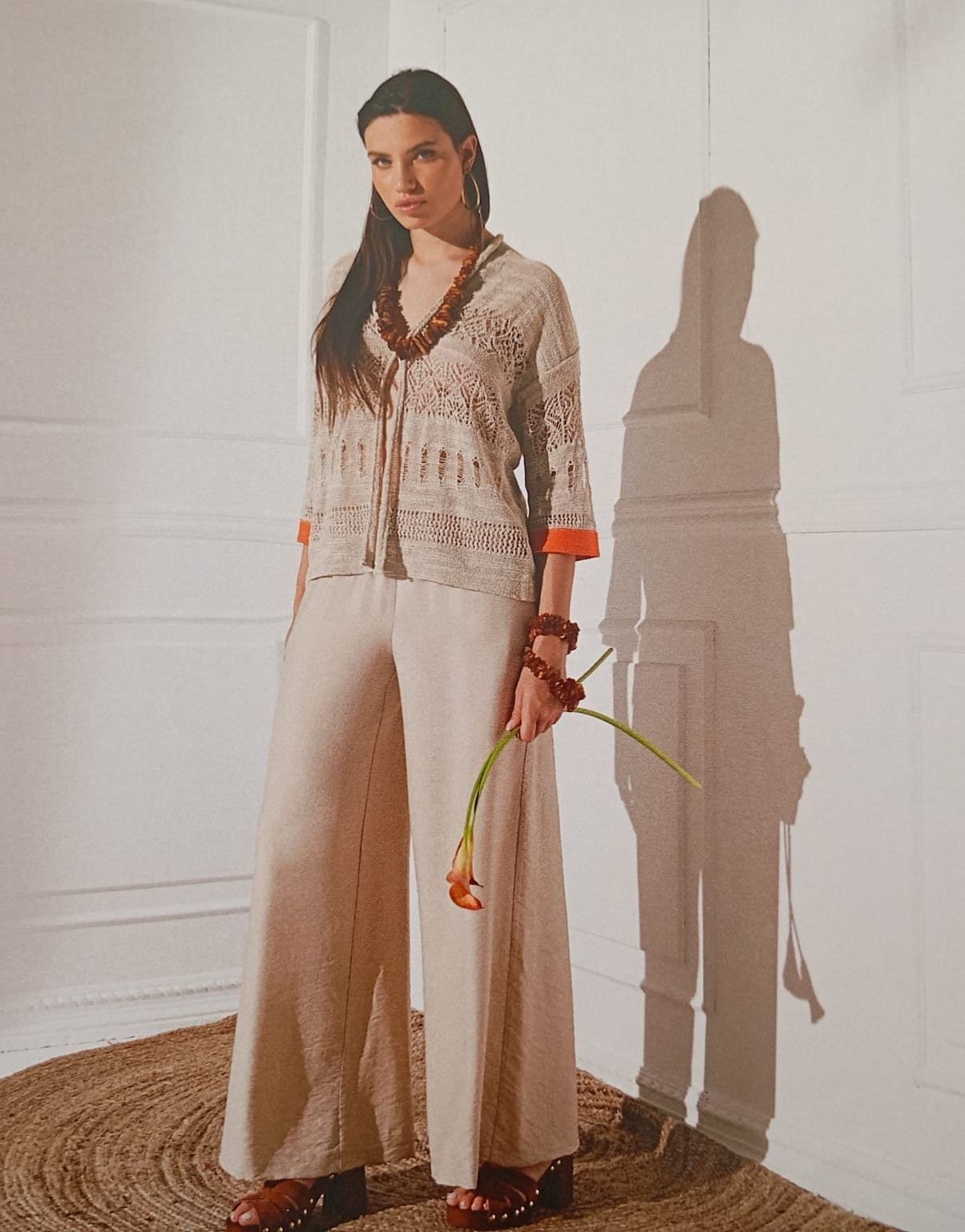 Una donna è in piedi davanti a un muro e tiene in mano un fiore.