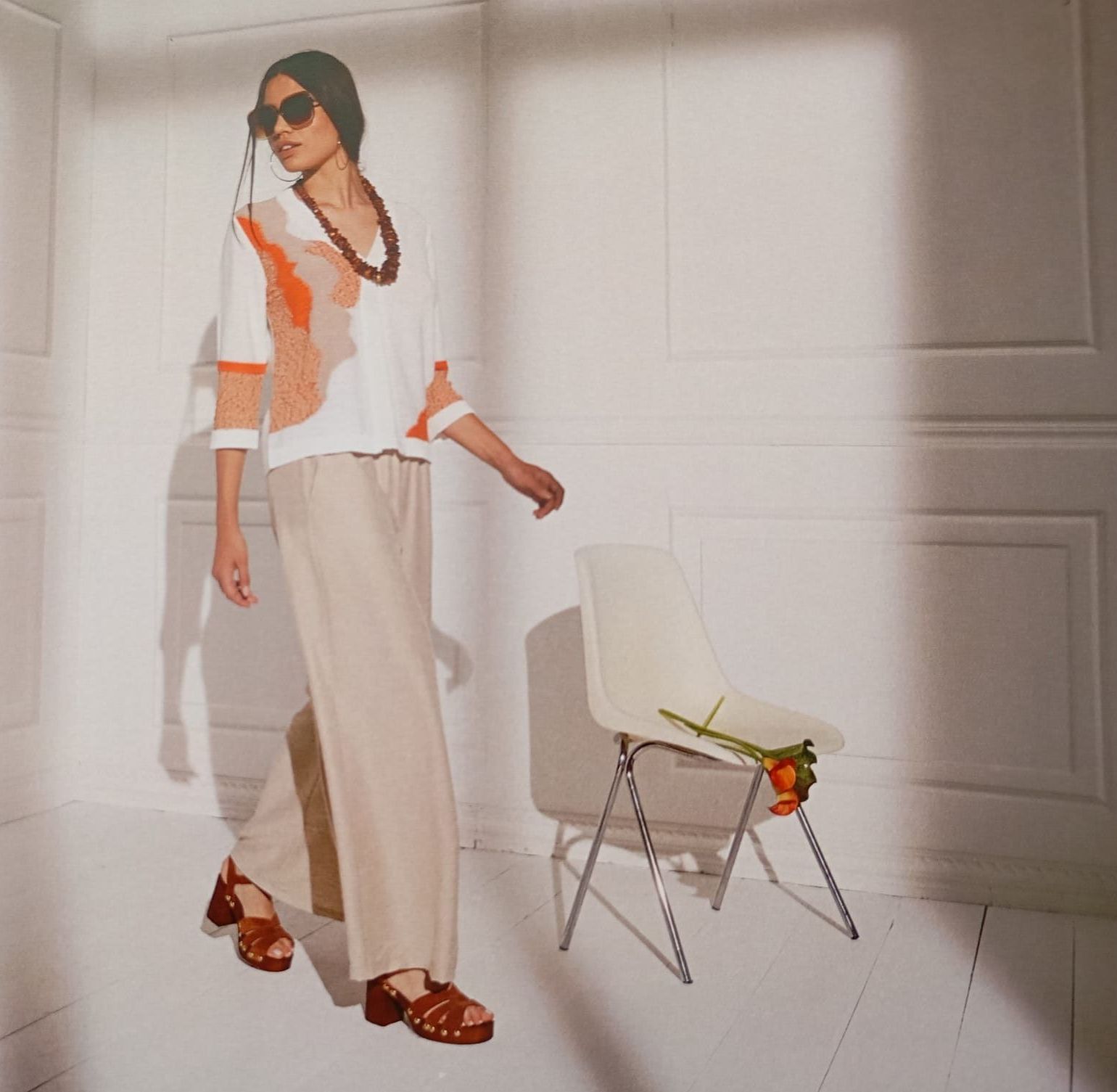 Una donna che indossa occhiali da sole è in piedi accanto a una sedia