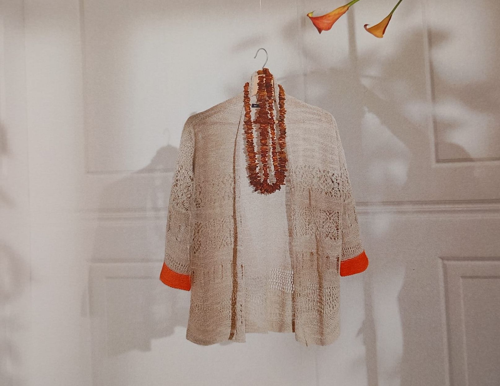 Un maglione e una collana sono appesi a una gruccia.