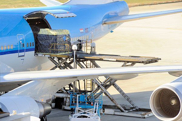 A large passenger jet is being loaded with cargo at an airport.