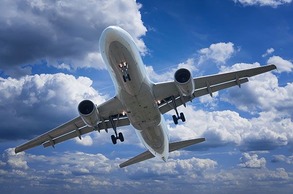 A large passenger jet is flying through a cloudy blue sky.