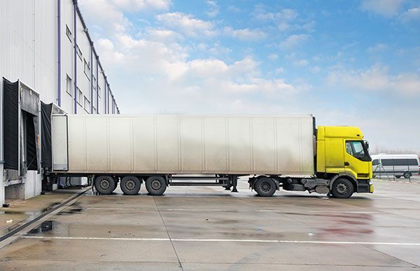 A yellow truck is parked in front of a warehouse.