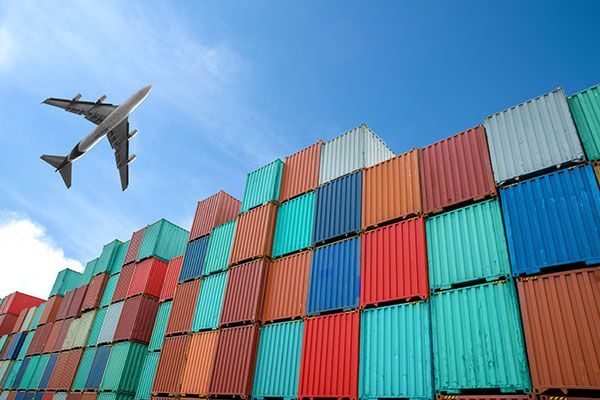 A plane is flying over a stack of shipping containers.