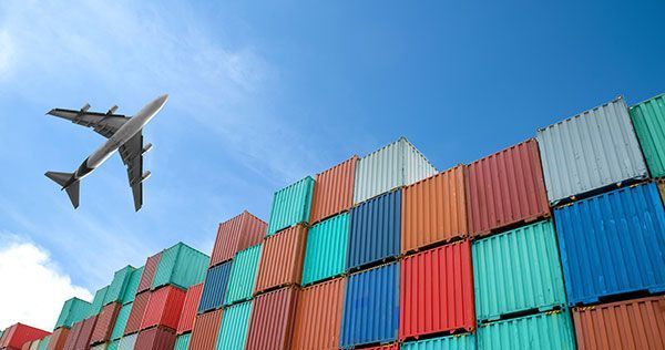 A plane is flying over a pile of shipping containers.