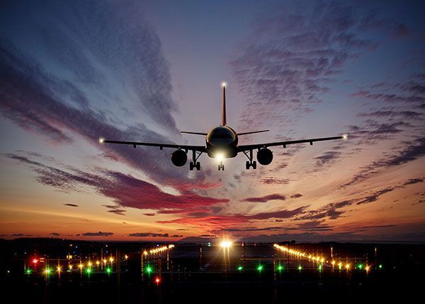 An airplane is taking off from an airport runway at sunset.