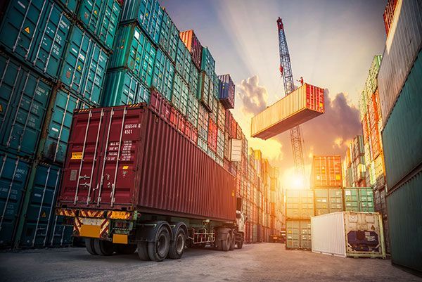 A truck is driving through a warehouse filled with shipping containers.
