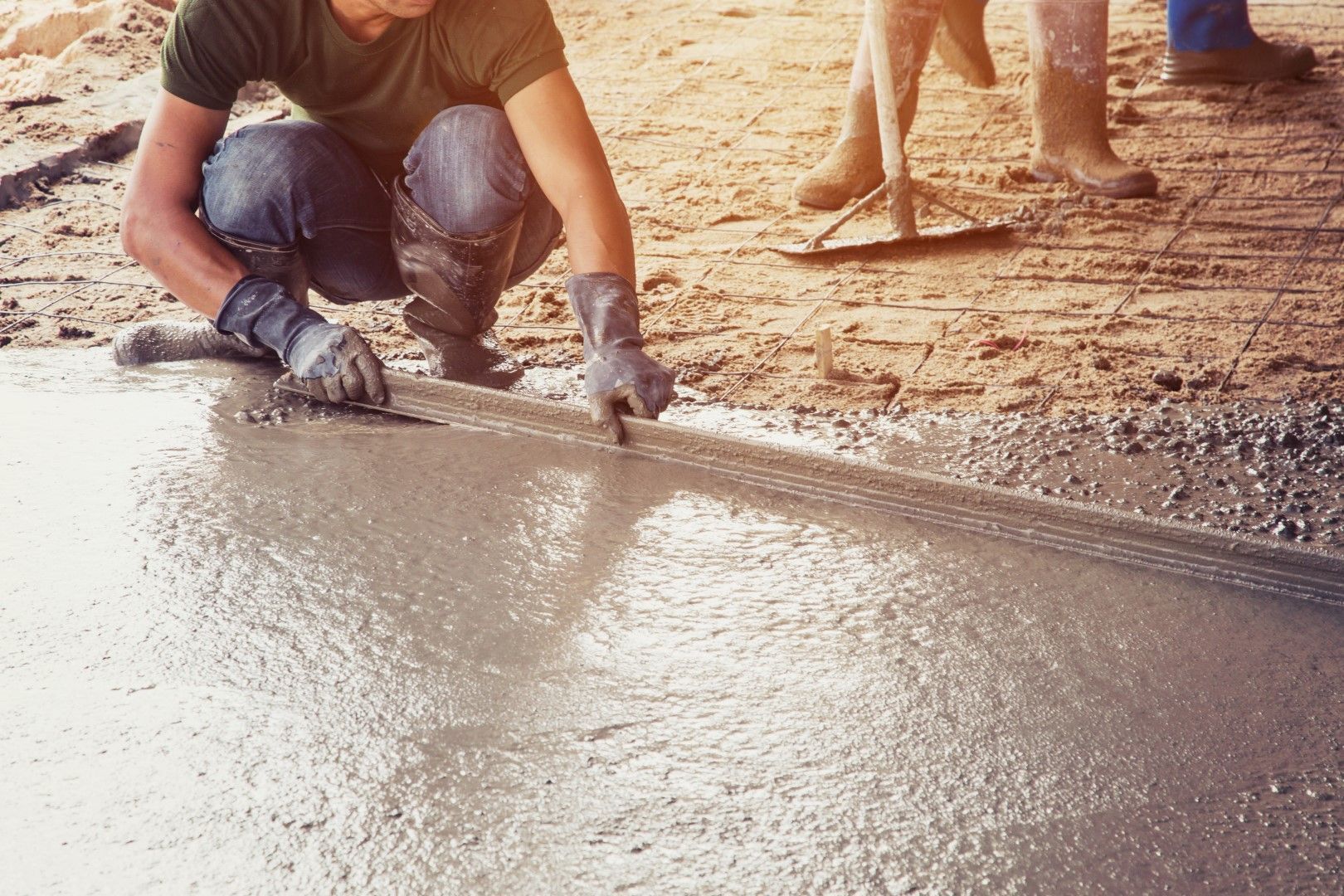 Person smoothing fresh concrete with a trowel, outdoors.