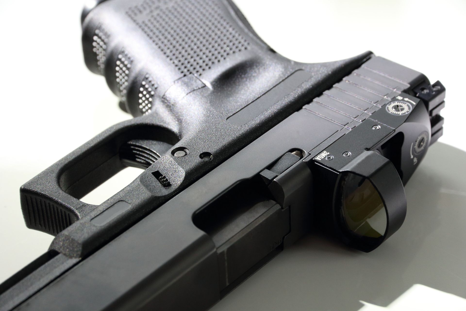 Black handgun with red dot sight on a white surface.