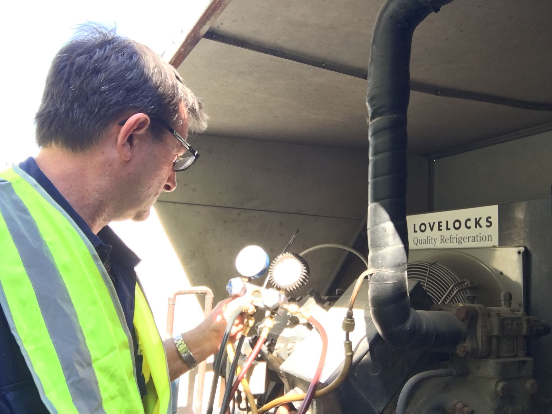 A Man is Standing on a Ladder Working on an Air Conditioner — Chillzone Refrigeration and Air Conditioning in Maleny, QLD
