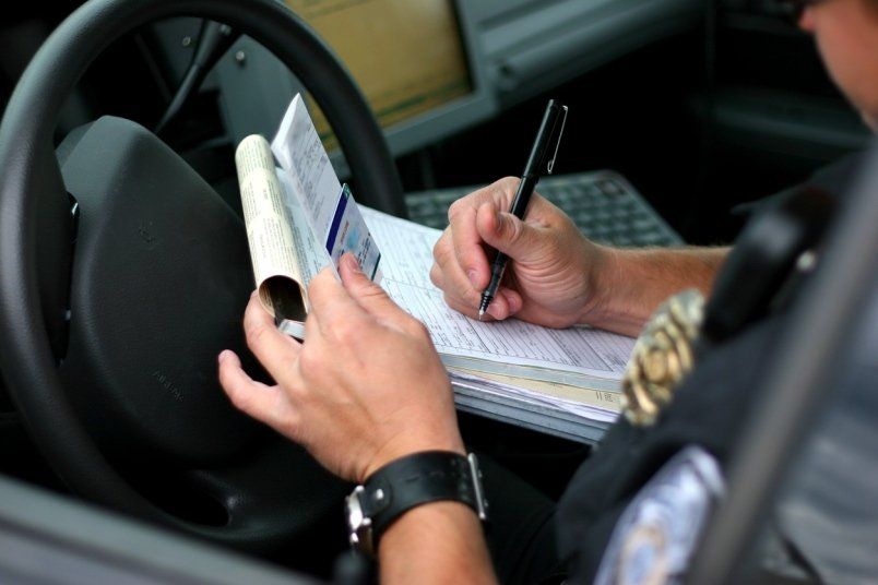 A police officer is writing a ticket in a car