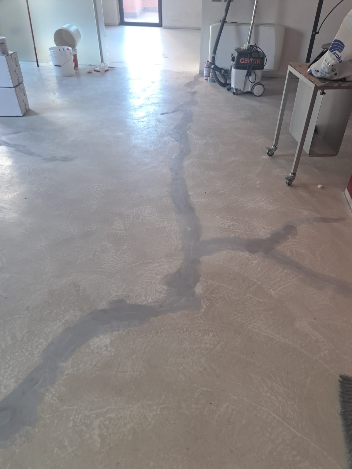 Pavimento in cemento con una lunga crepa scura; cantiere.
