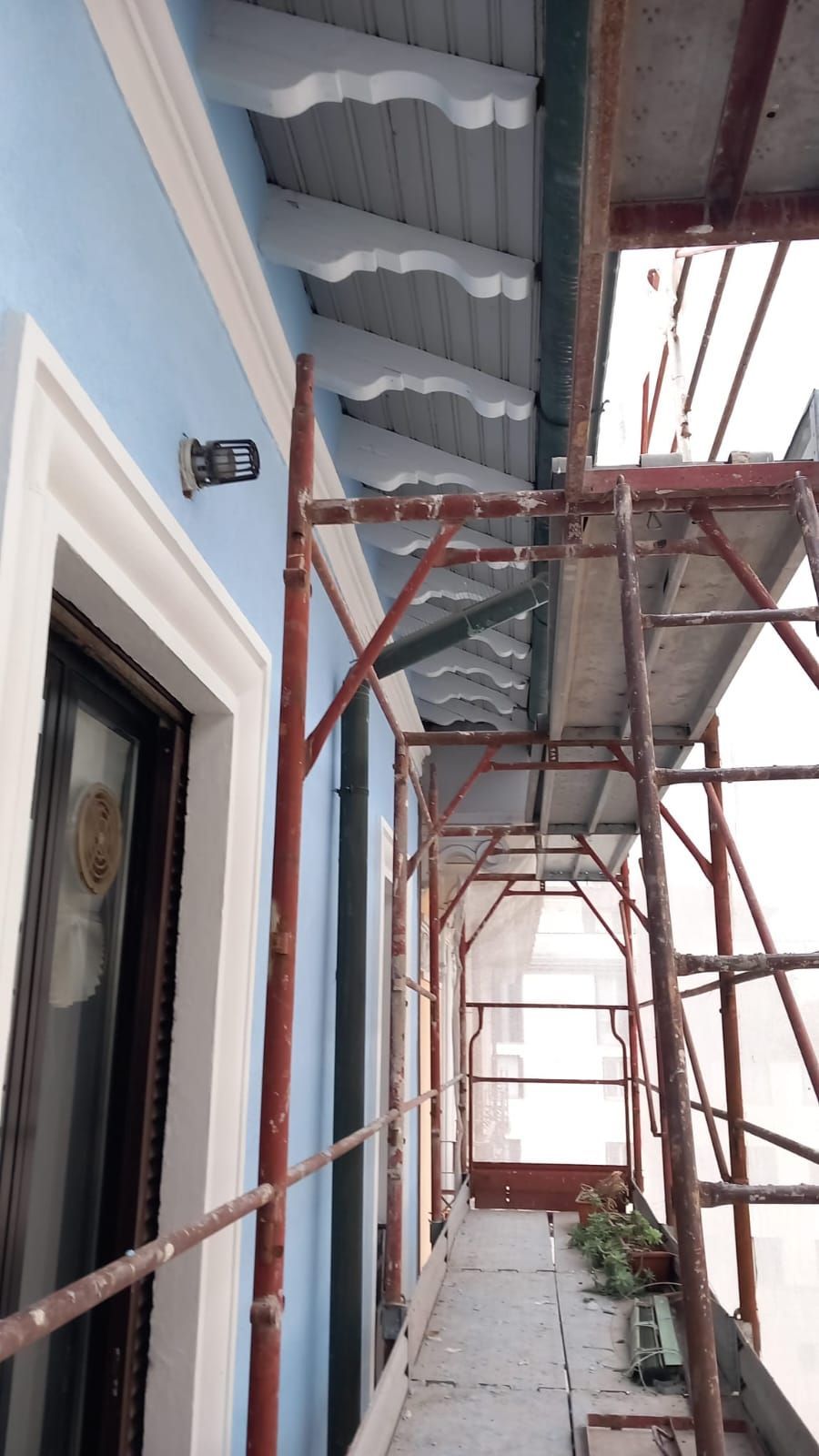 Un edificio blu con finiture bianche su cui si stanno lavorando le impalcature.