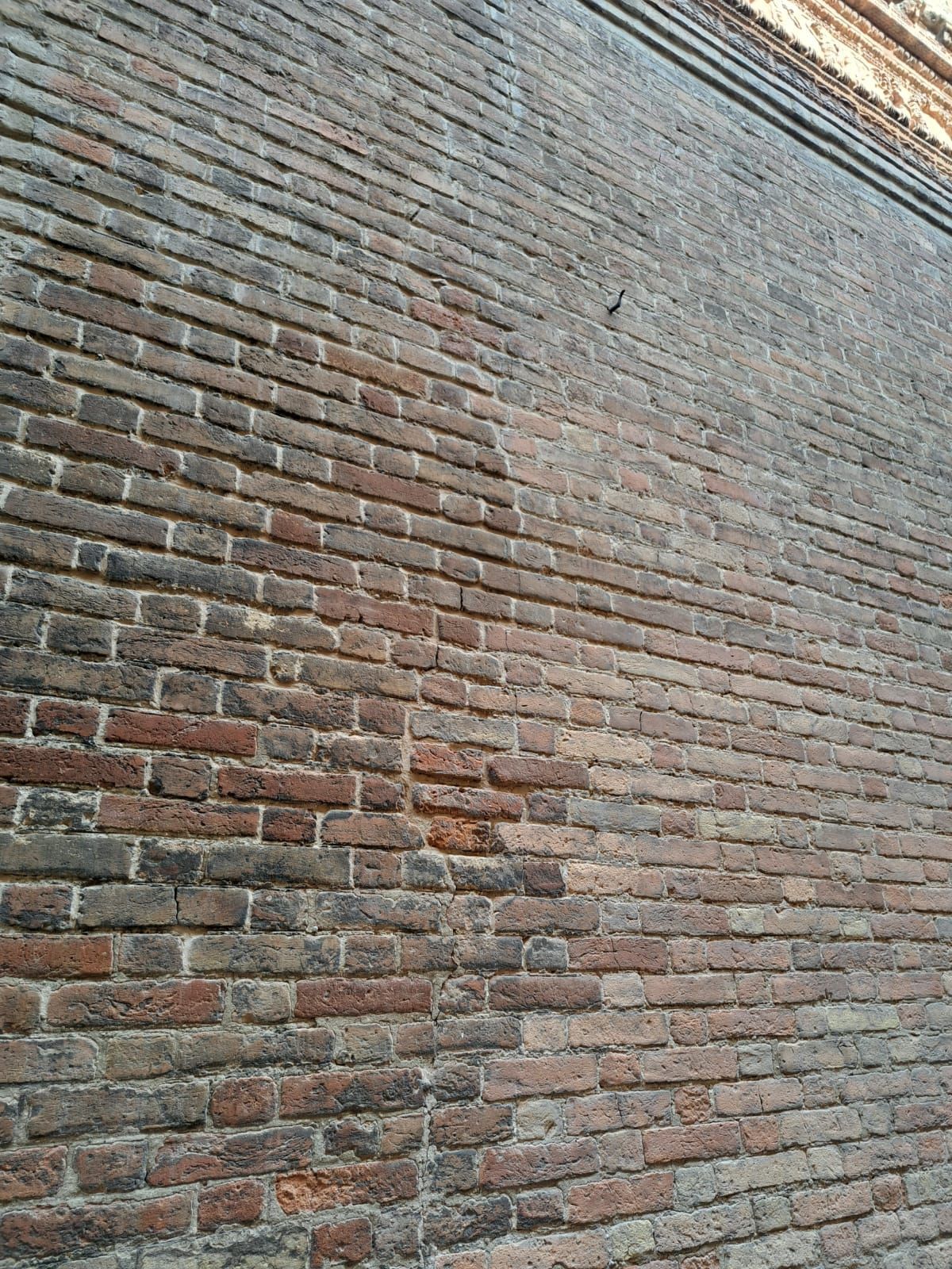 Muro di mattoni con una pendenza dal scuro al chiaro, probabilmente dovuta alla pulizia.