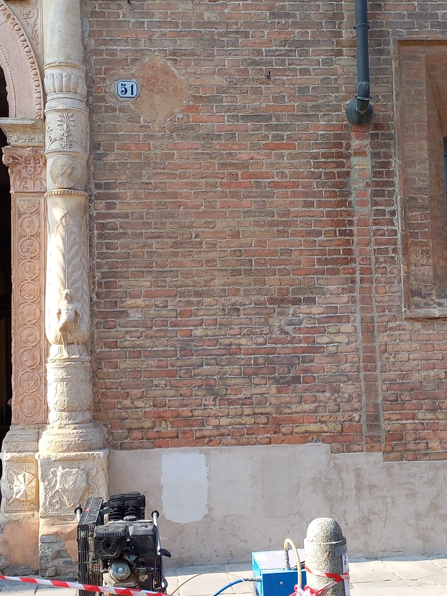 Esterno di un edificio in mattoni con il numero 131, una macchina di servizio e un pilastro decorativo.