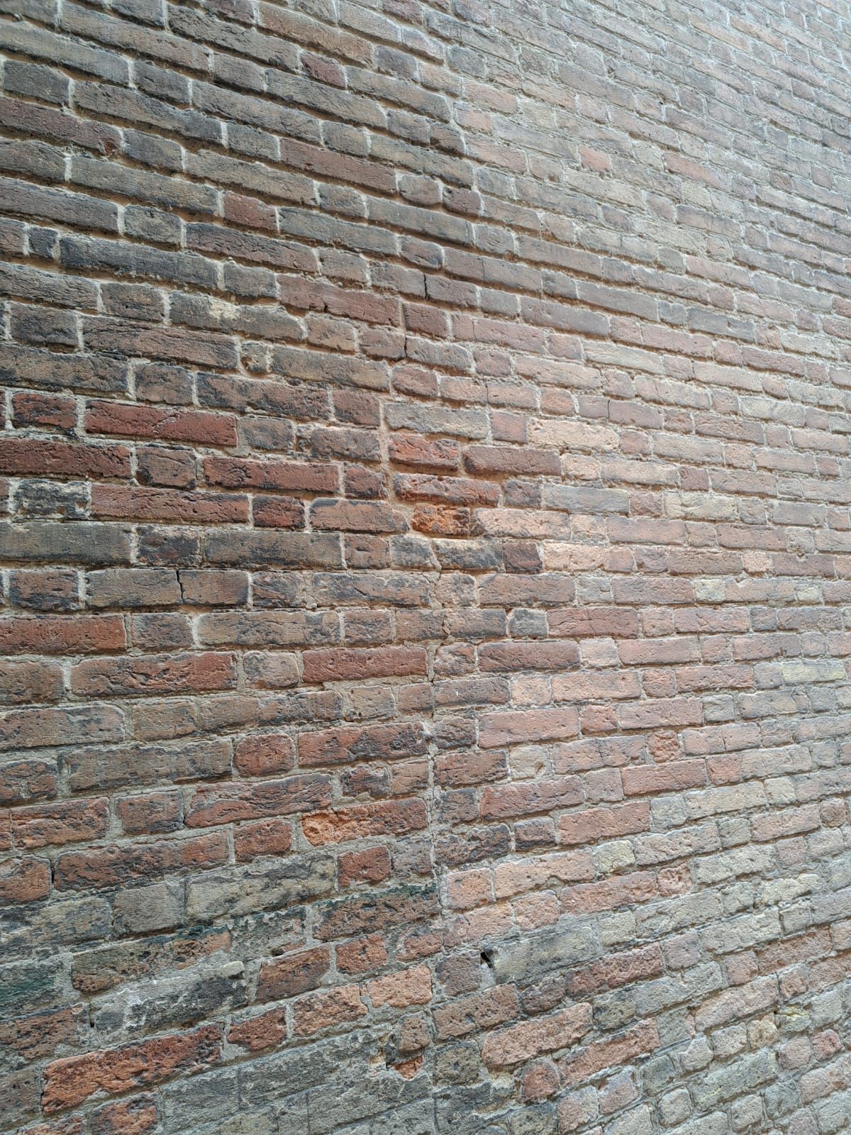 Muro di mattoni, per lo più mattoni rosso-marroni, alcuni più chiari; aspetto usurato.