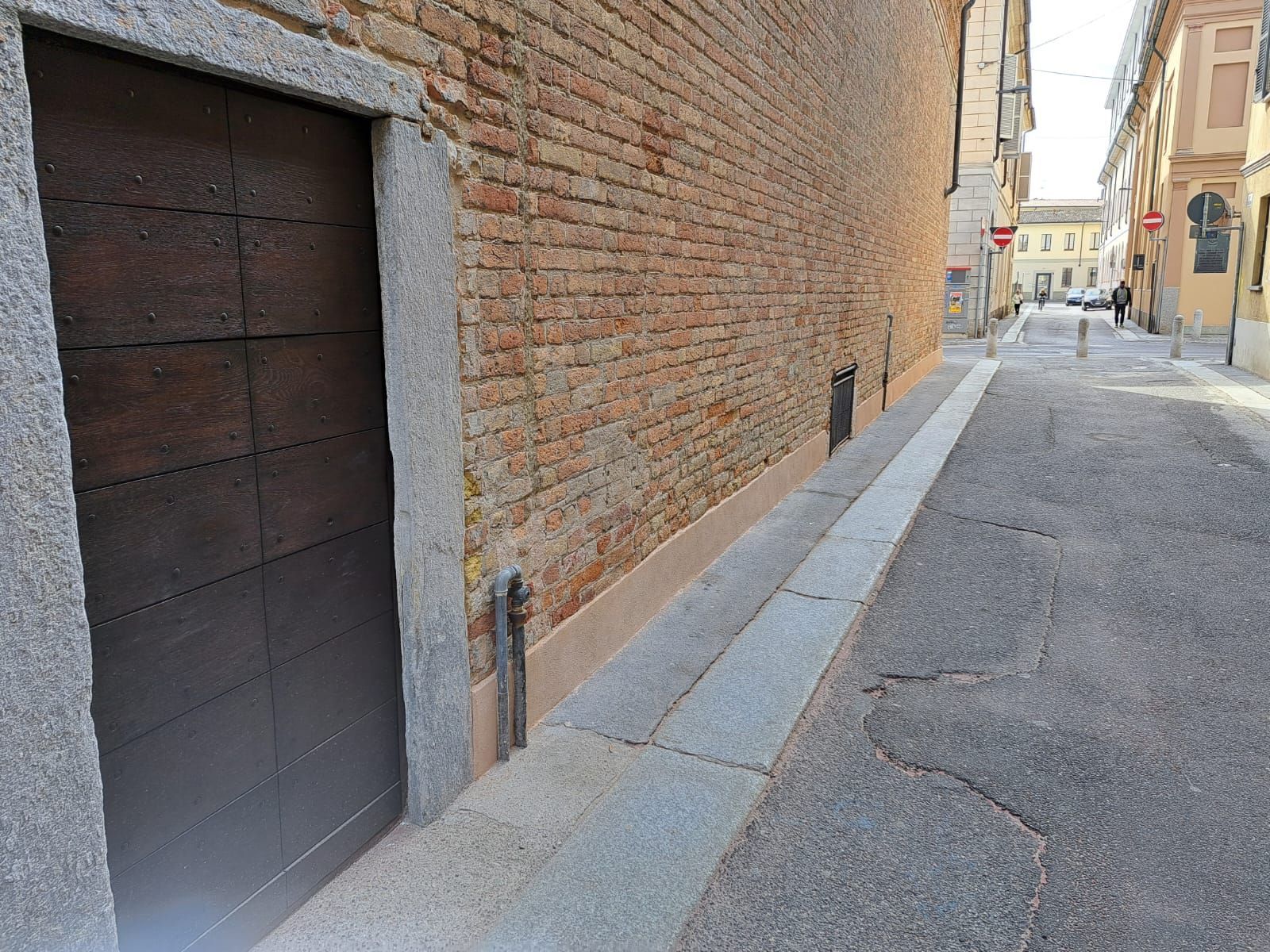 Porta di legno e edificio in mattoni su una stretta strada acciottolata.