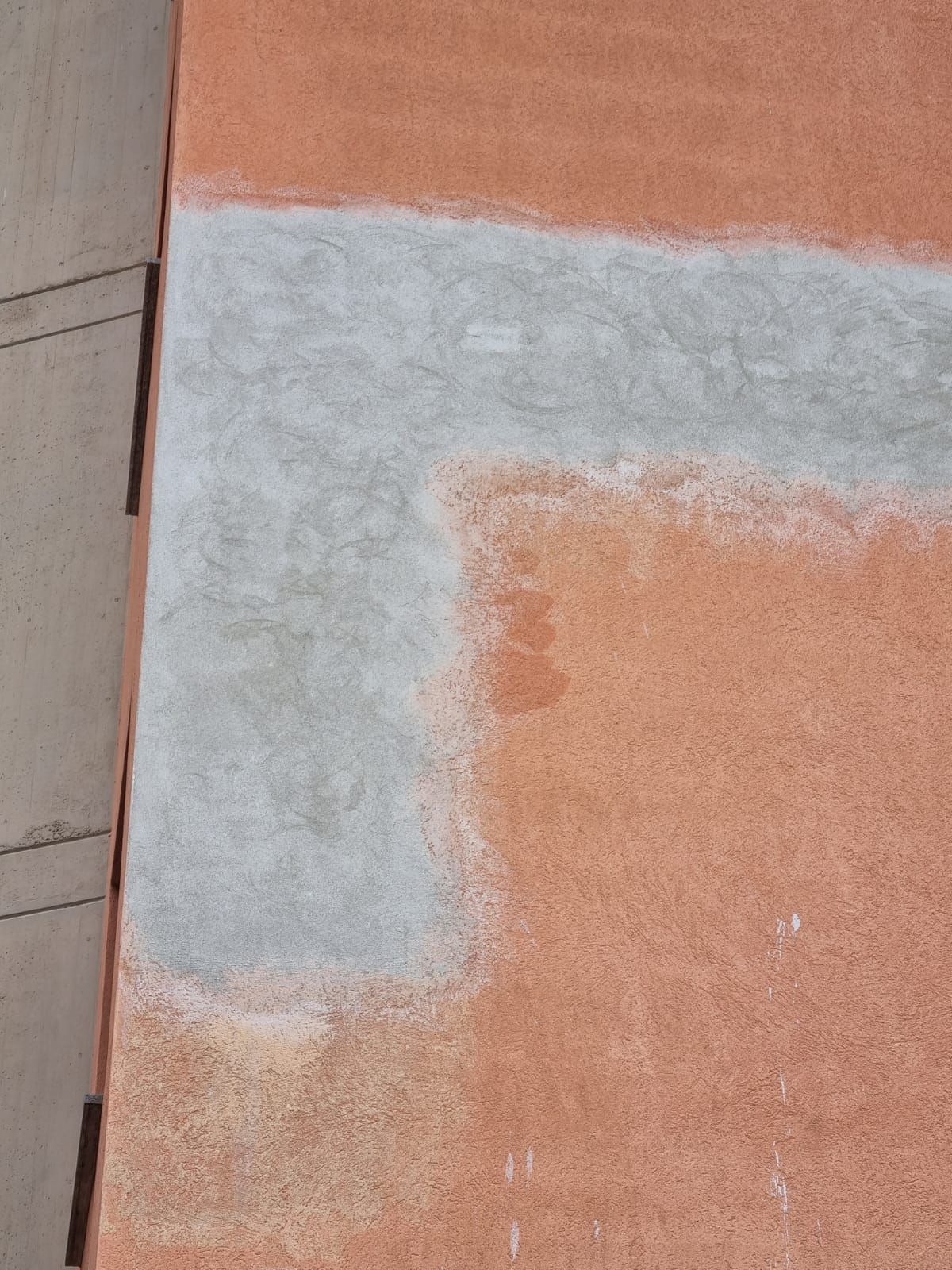 Parete testurizzata arancione con una grande area grigia e scolorita.