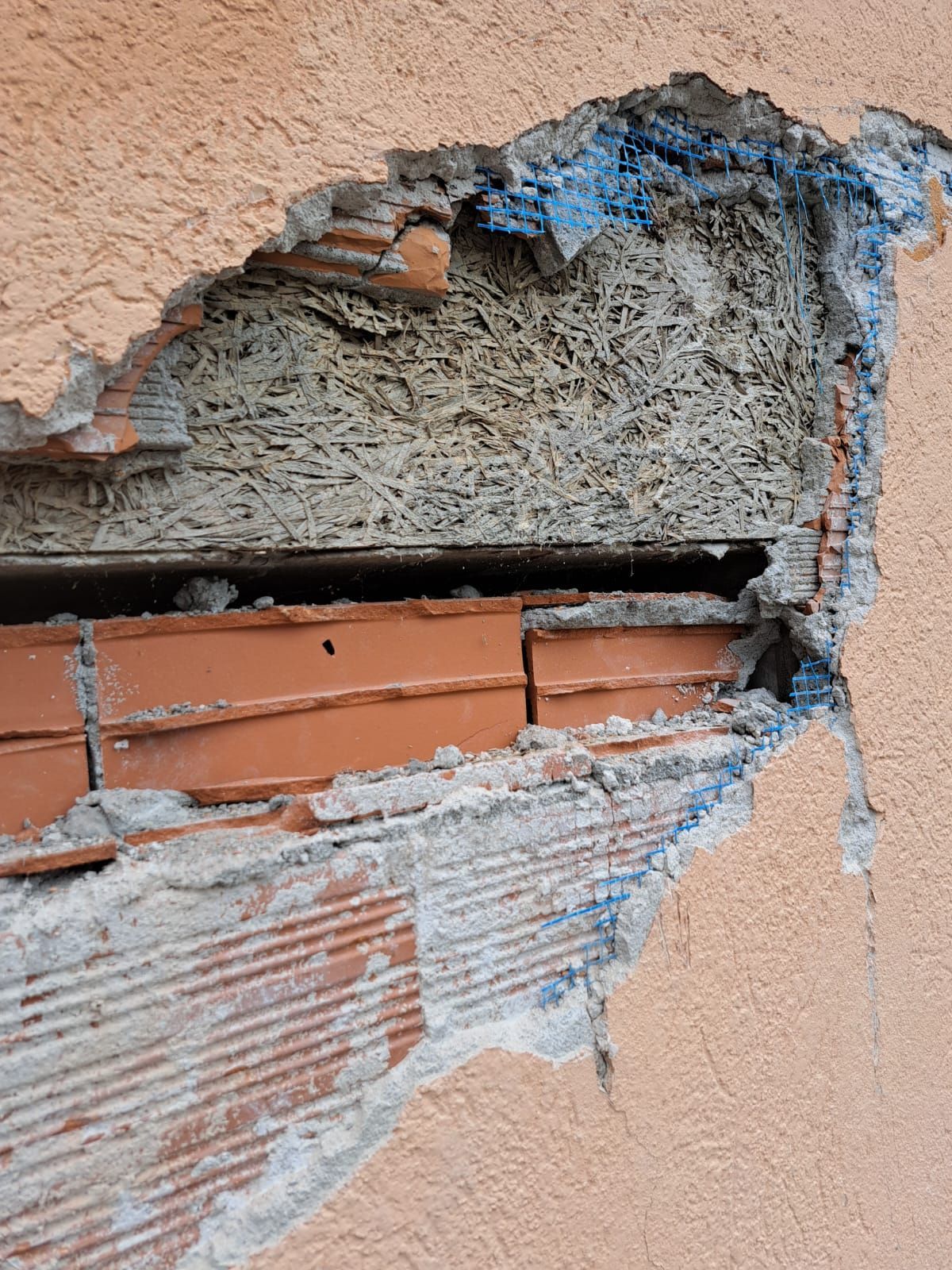 Muro esterno danneggiato con mattoni a vista, isolamento e stucco; un cantiere edile.