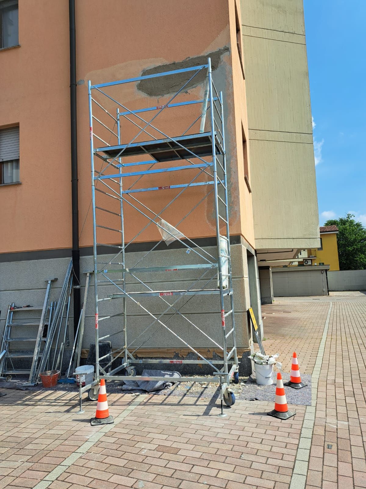 Impalcature contro un edificio in fase di ristrutturazione. Coni arancioni delimitano l'area di lavoro.