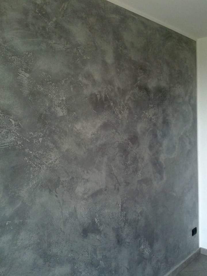 Parete grigia, ruvida, dall'aspetto screziato e nuvoloso, probabilmente una finitura decorativa.