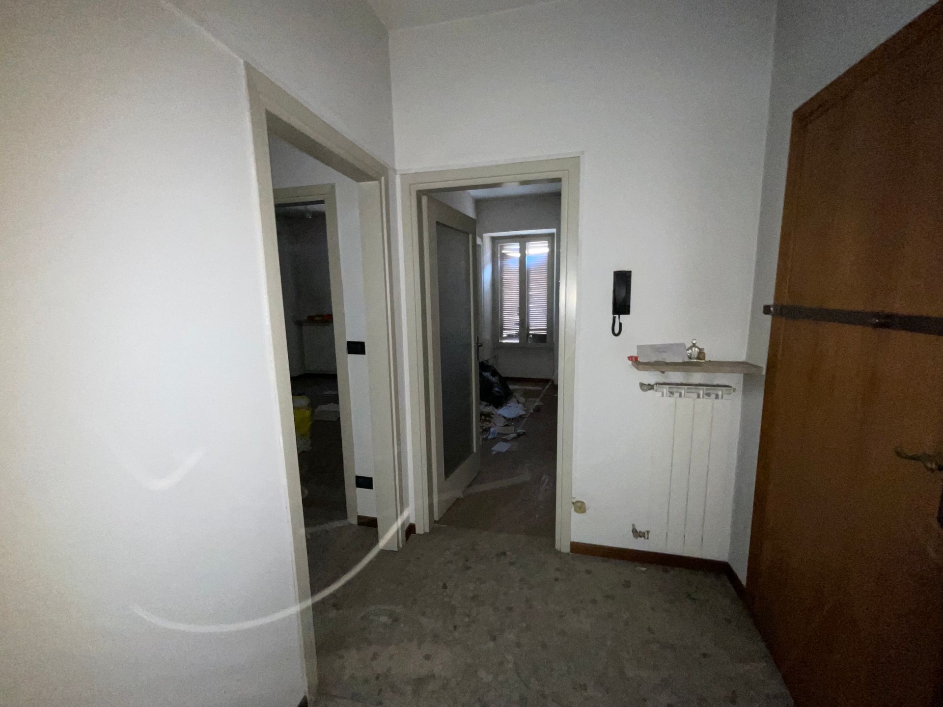 Corridoio interno con porte, un termosifone e una porta di legno.