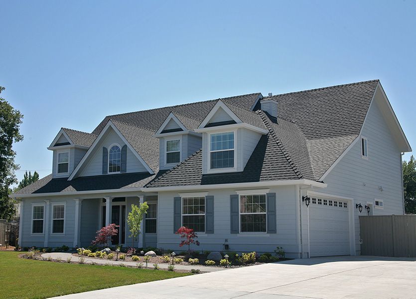 Two-story, light blue house with gray roof, windows, and attached garage. Sunny day.