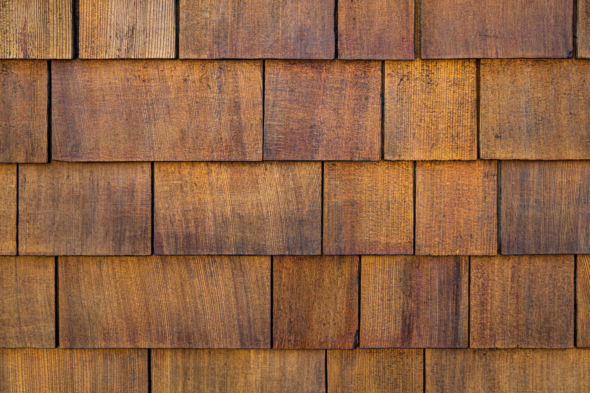 Close-up of weathered, rectangular wood shingles in varying shades of brown.