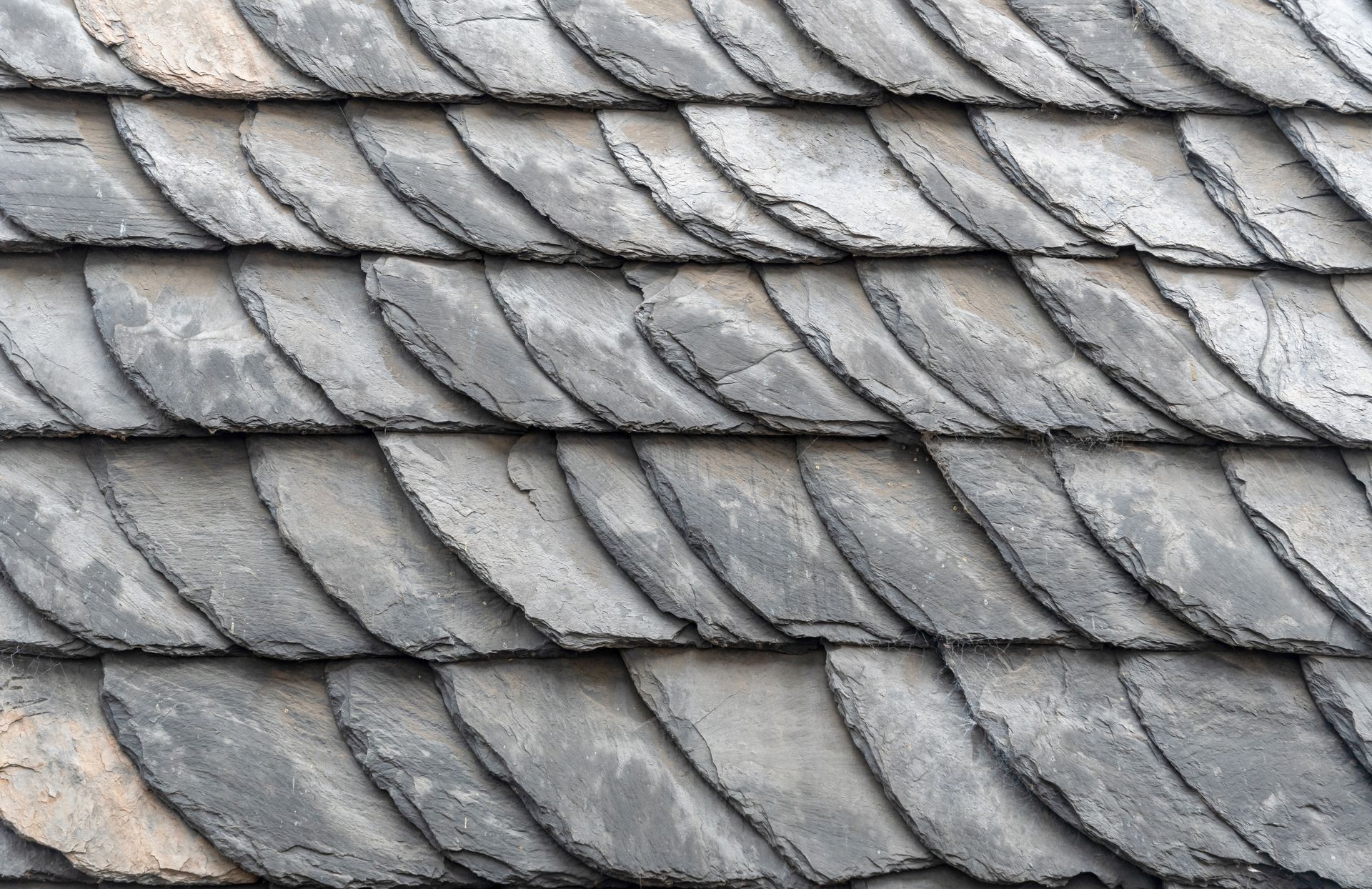 Close-up view of gray, overlapping slate roof tiles.