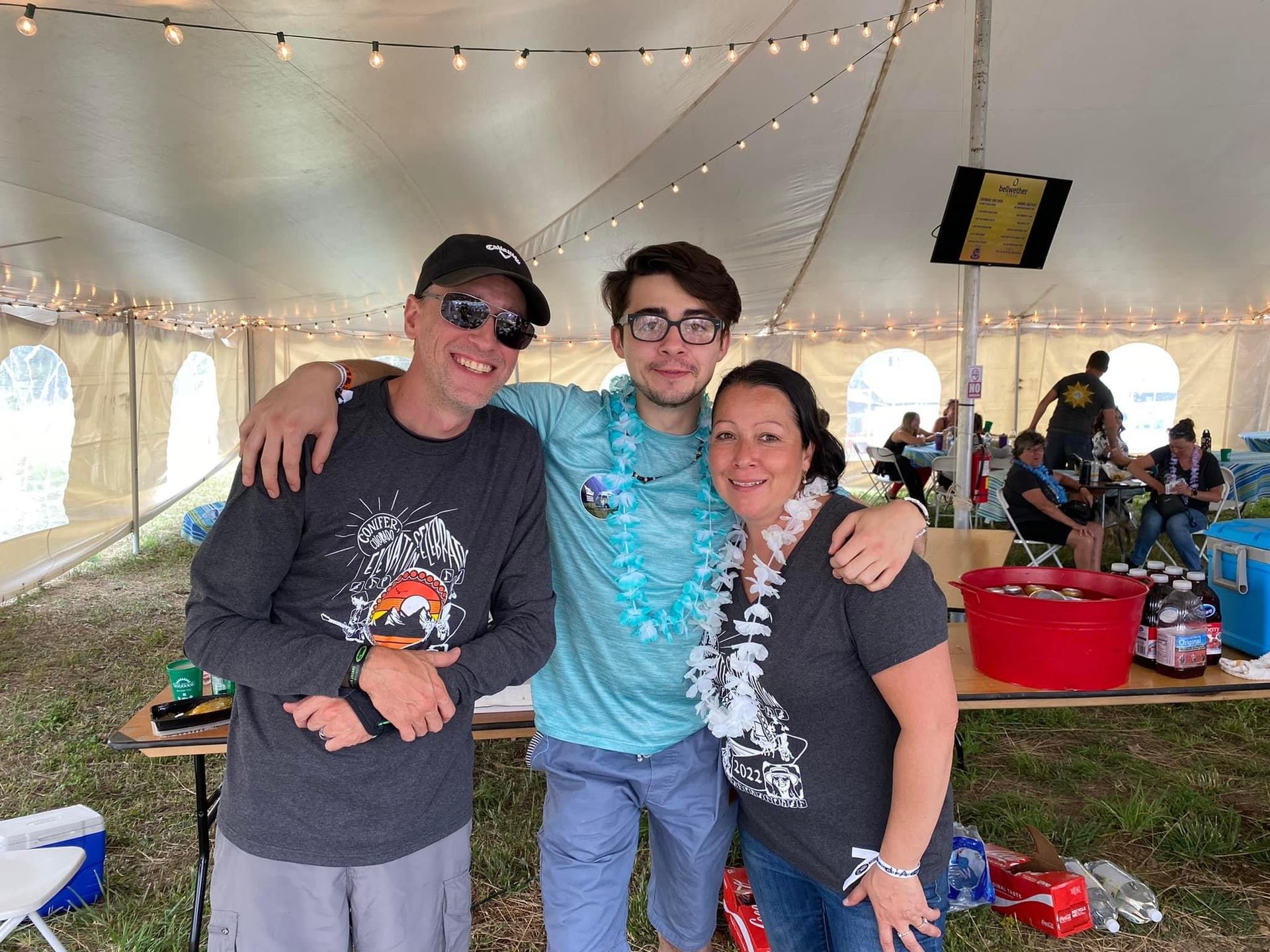 Three people are posing for a picture in front of a tent.